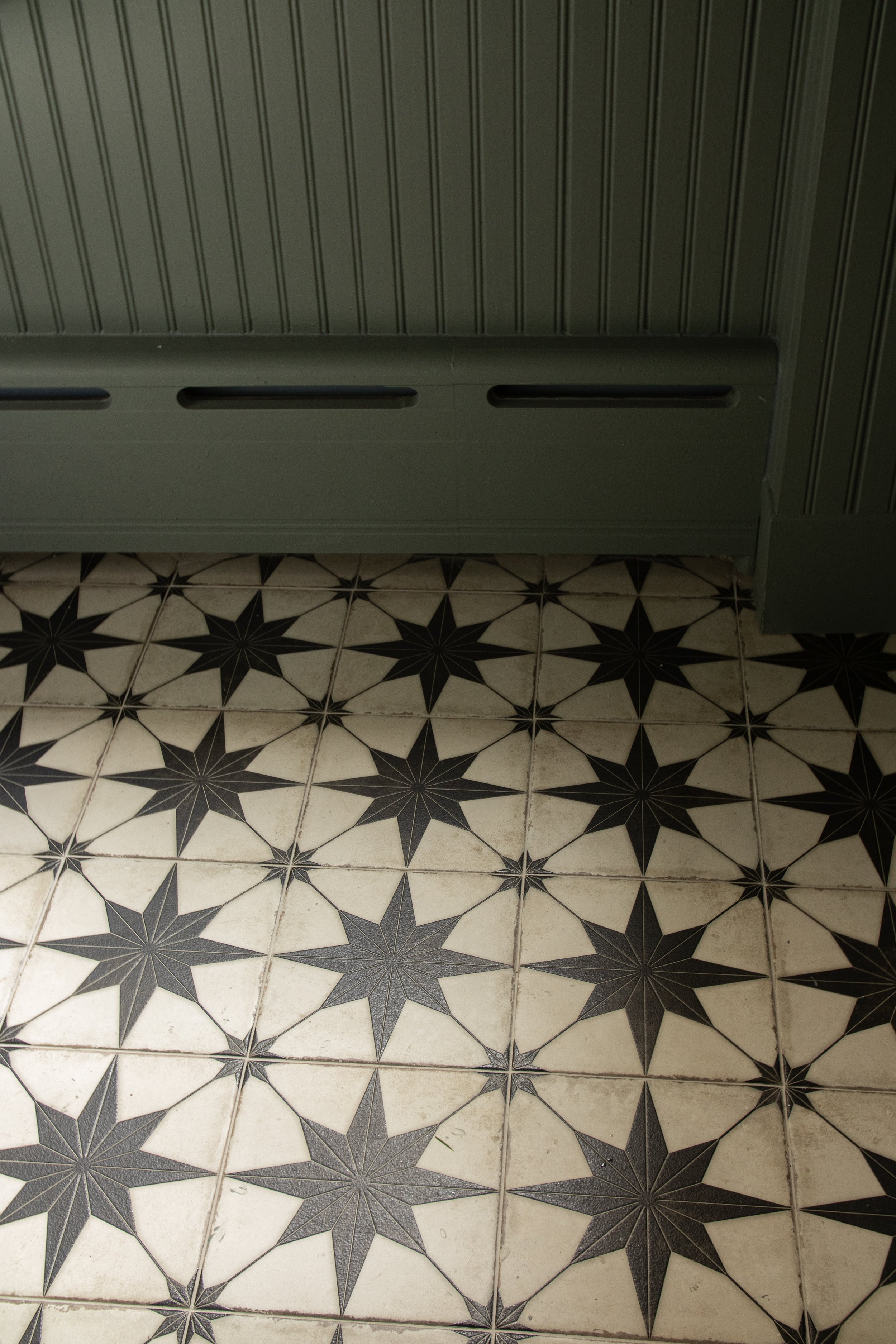 Black and white patterned tile floor with a green wall and cabinet at the top of the image.