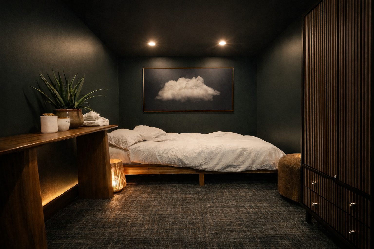 A cozy bedroom with dark green walls, a bed with white bedding, a framed cloud picture above, a wooden side table with potted plants and towels, a textured floor lamp, and a wooden wardrobe.