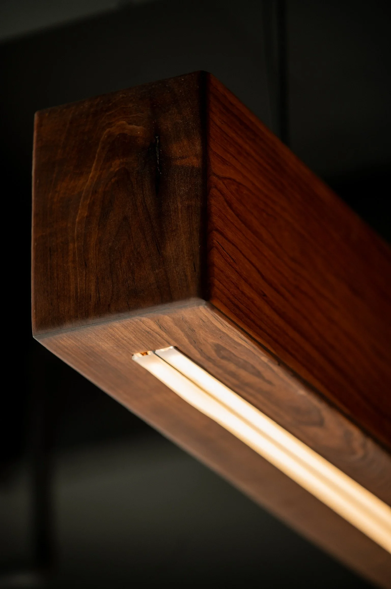 Close-up of a wooden surface with a built-in light strip, showing the corner of a wooden furniture piece with visible wood grain and polished finish.