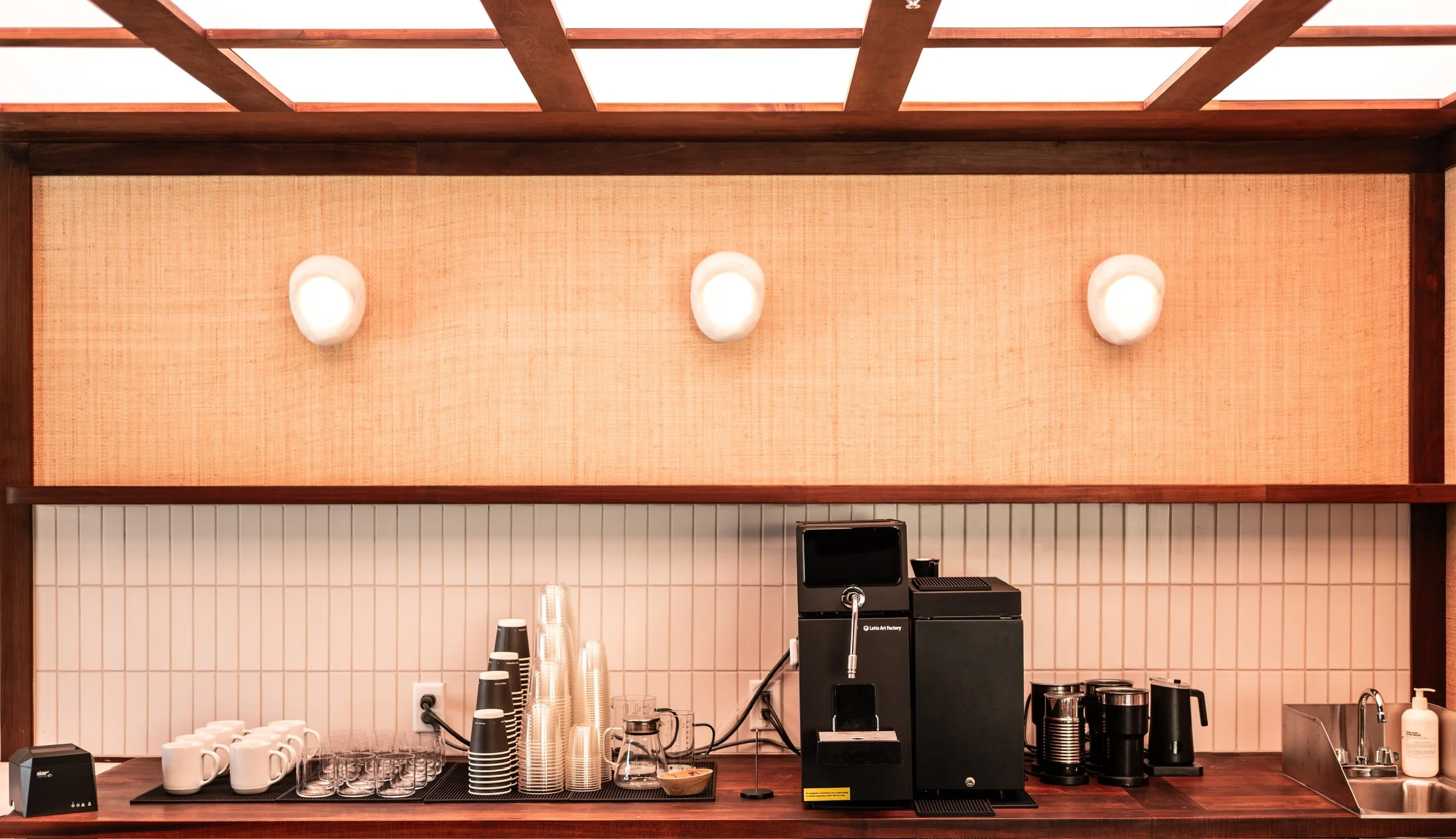Coffee station with cups, glasses, coffee machine, and supplies on a counter in a cafe or restaurant.