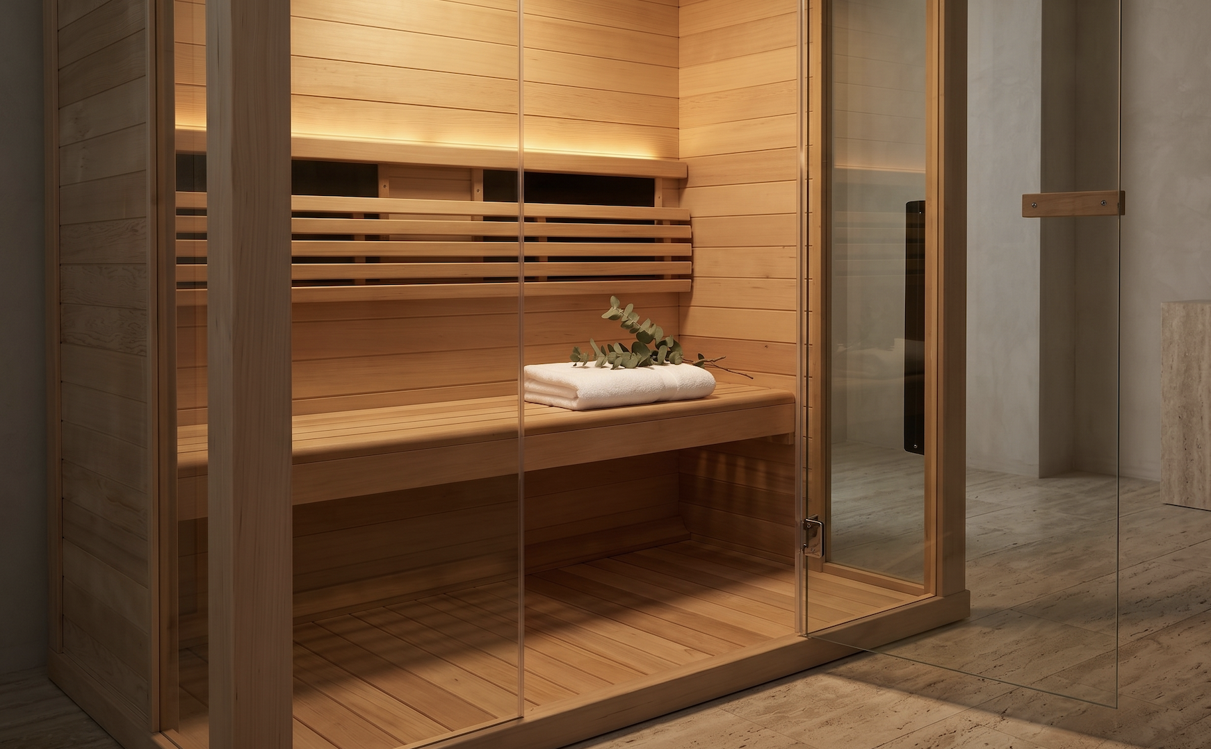 Een ruime, stenen sauna met houtenbank en decoratie van een witte handdoek en groene bladeren.