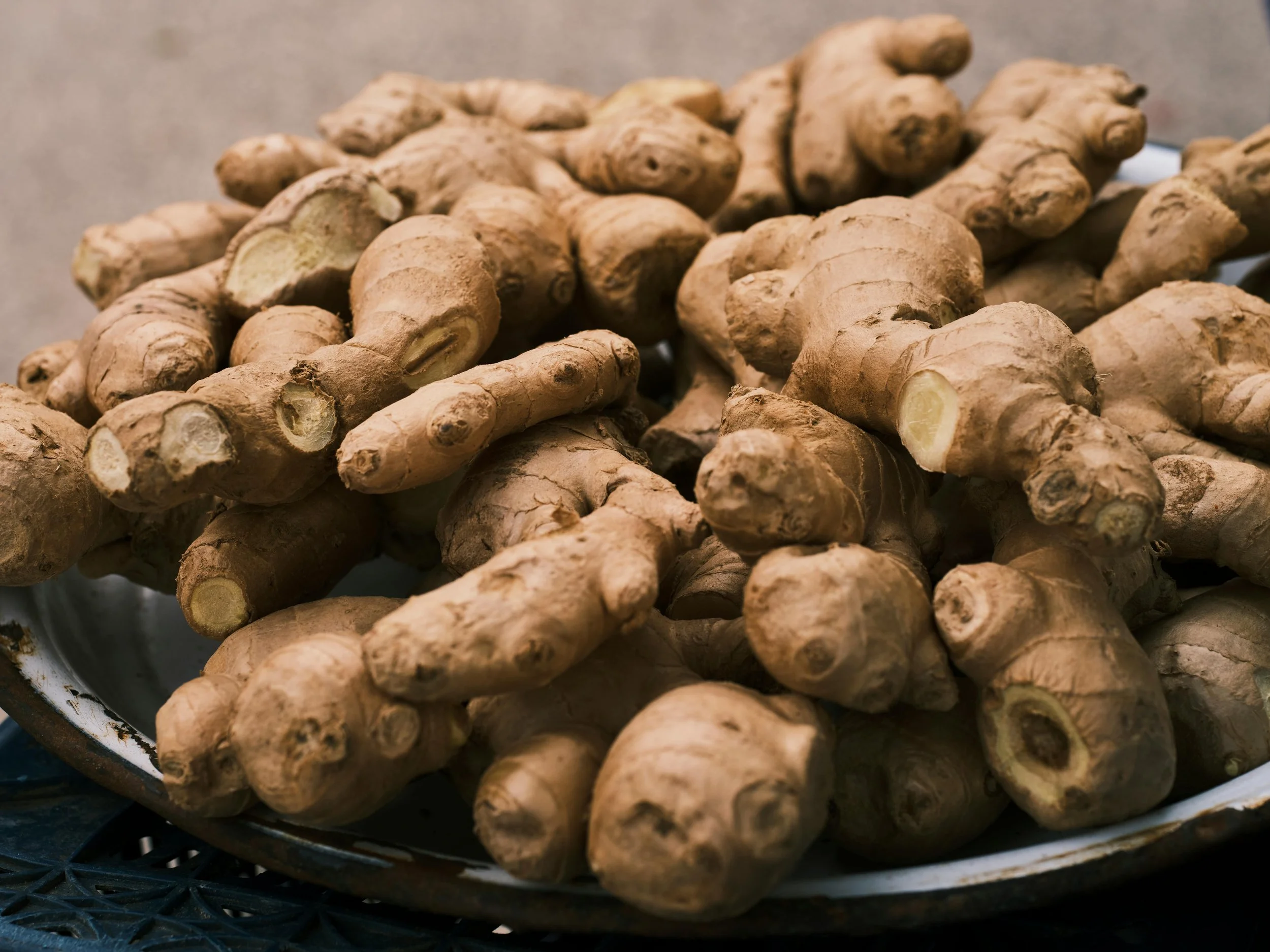 A pile of fresh ginger roots on a ceramic plate.