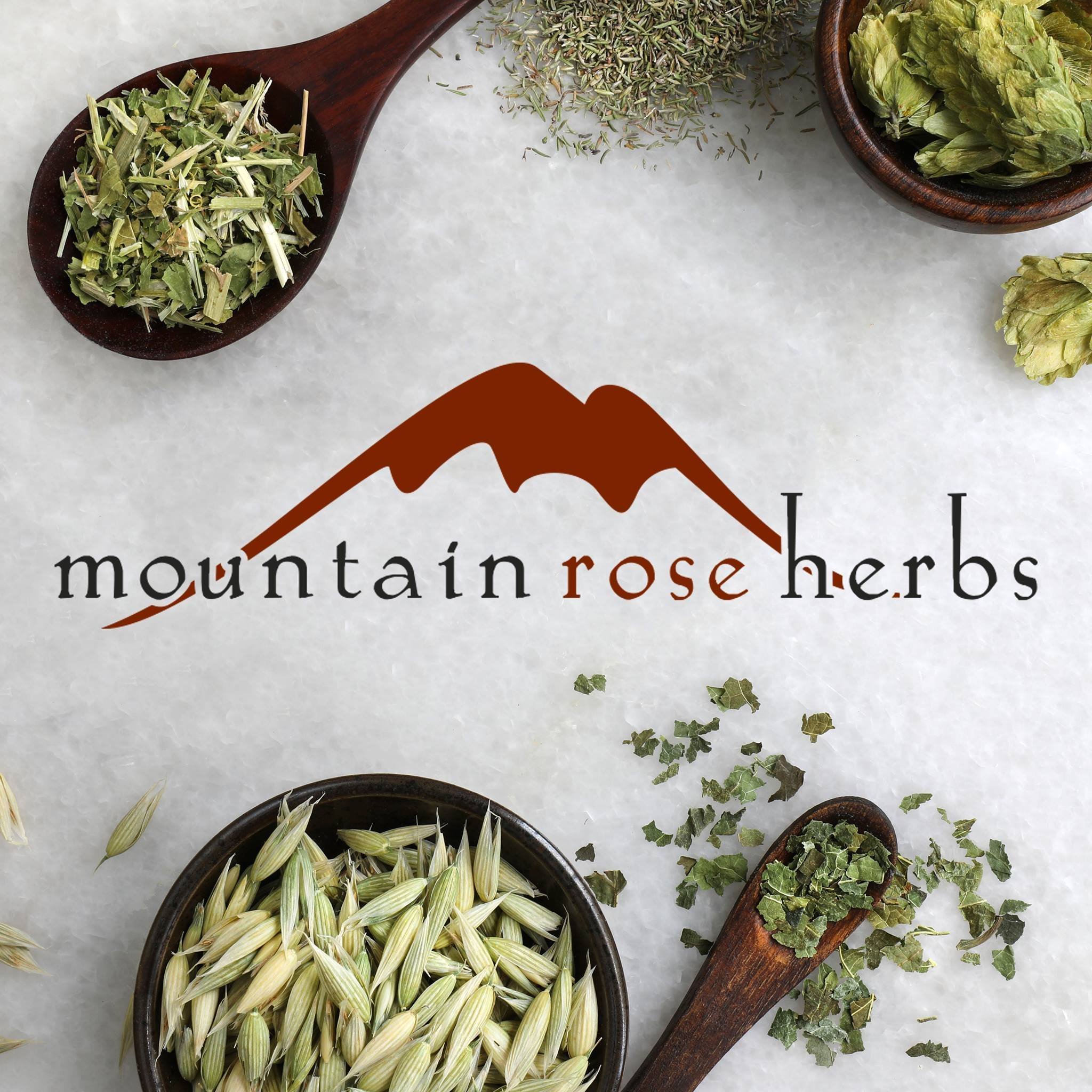 Assorted dried herbs and plants surrounding a logo for Mountain Rose Herbs with a mountain graphic beneath the text