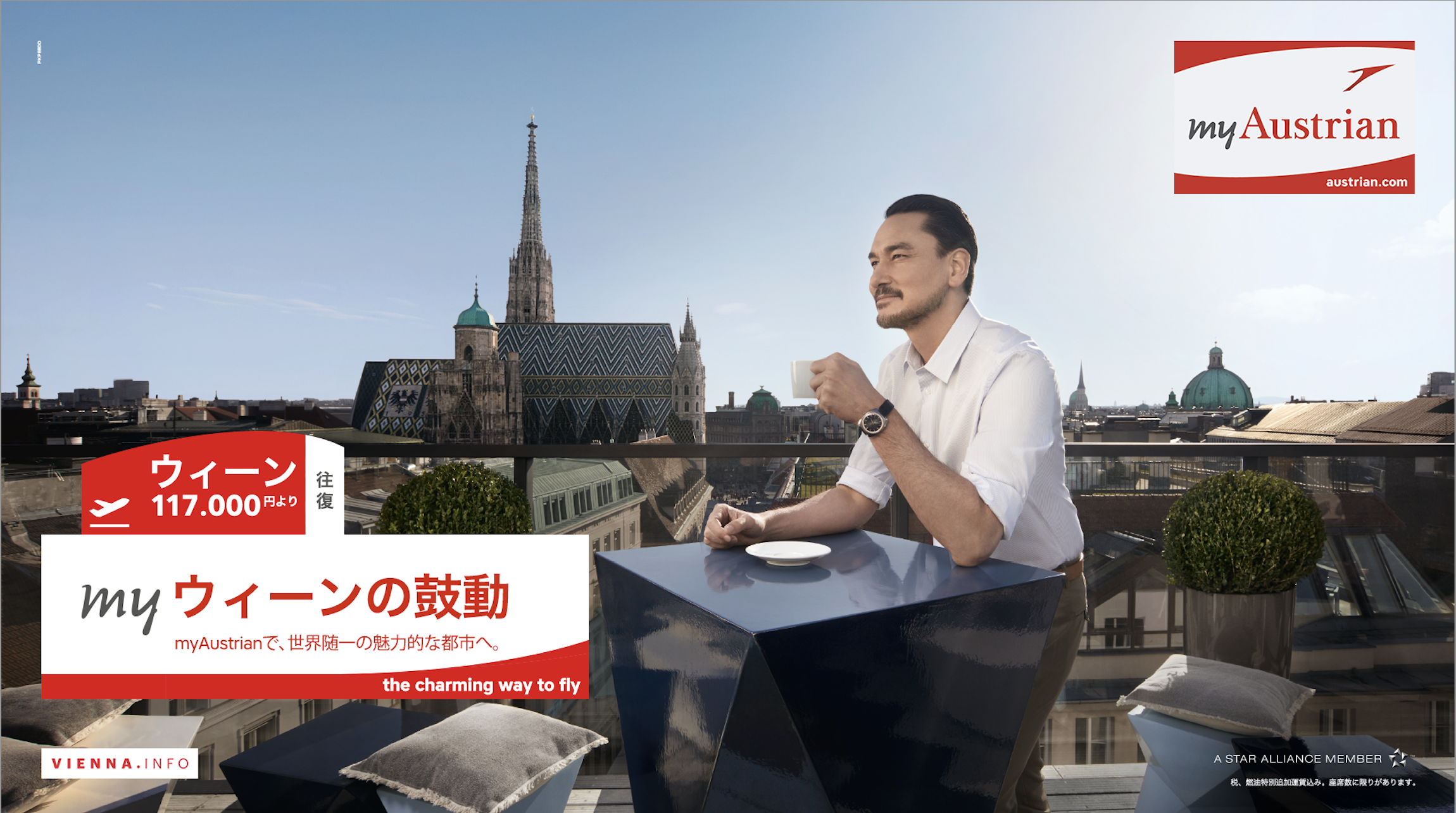 Ein Mann sitzt auf einem Balkon mit Sicht auf die Dächer von Wien und trinkt Kaffee. Es ist ein sonniger Tag. Das Bild enthält auch Text in Japanisch und Englisch, Werbung für Dubai Airlines. Im oberen rechten Ecke ist das Logo von myAustrian.