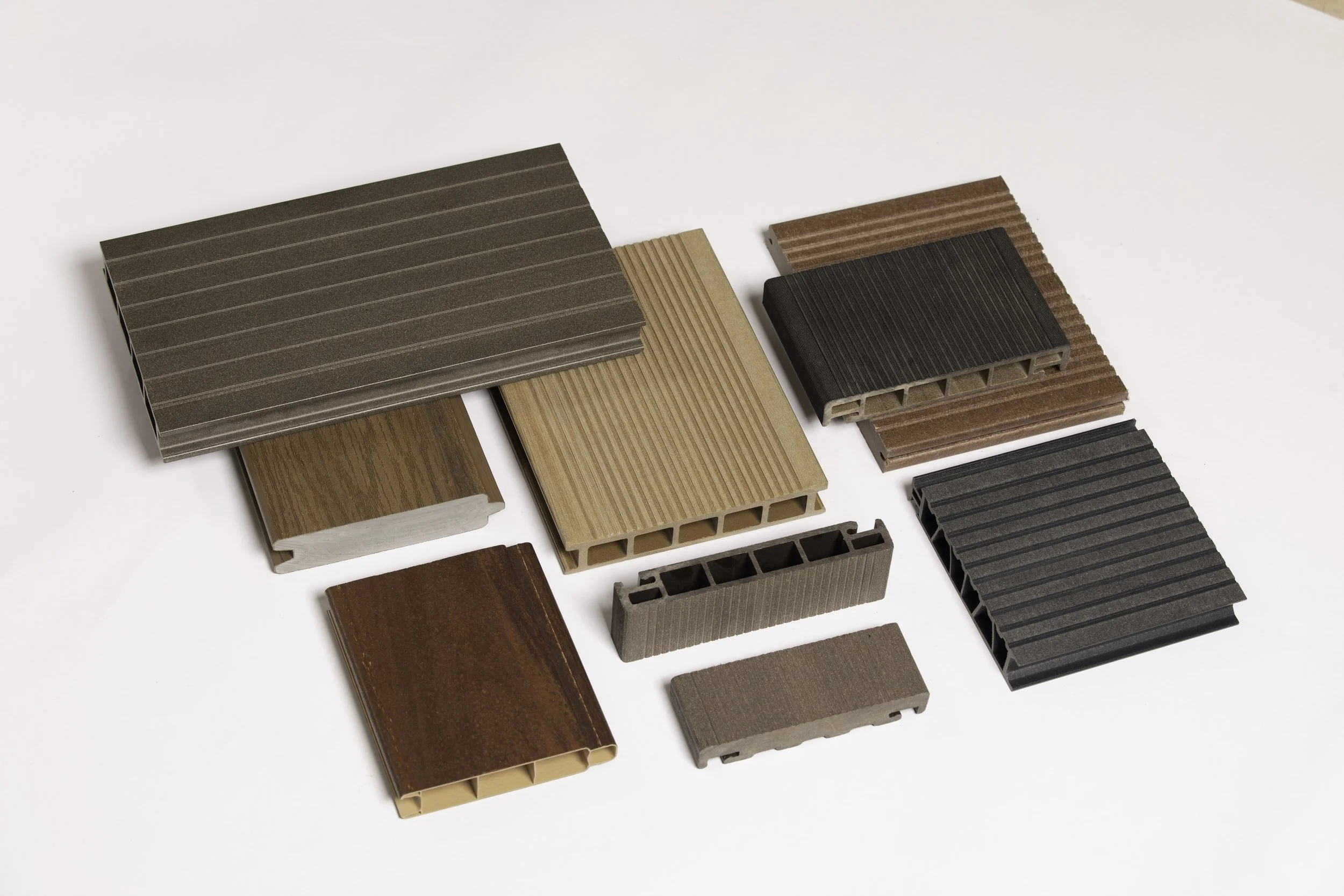 Various types of brown and black plastic and composite building materials shaped into rectangular tiles.