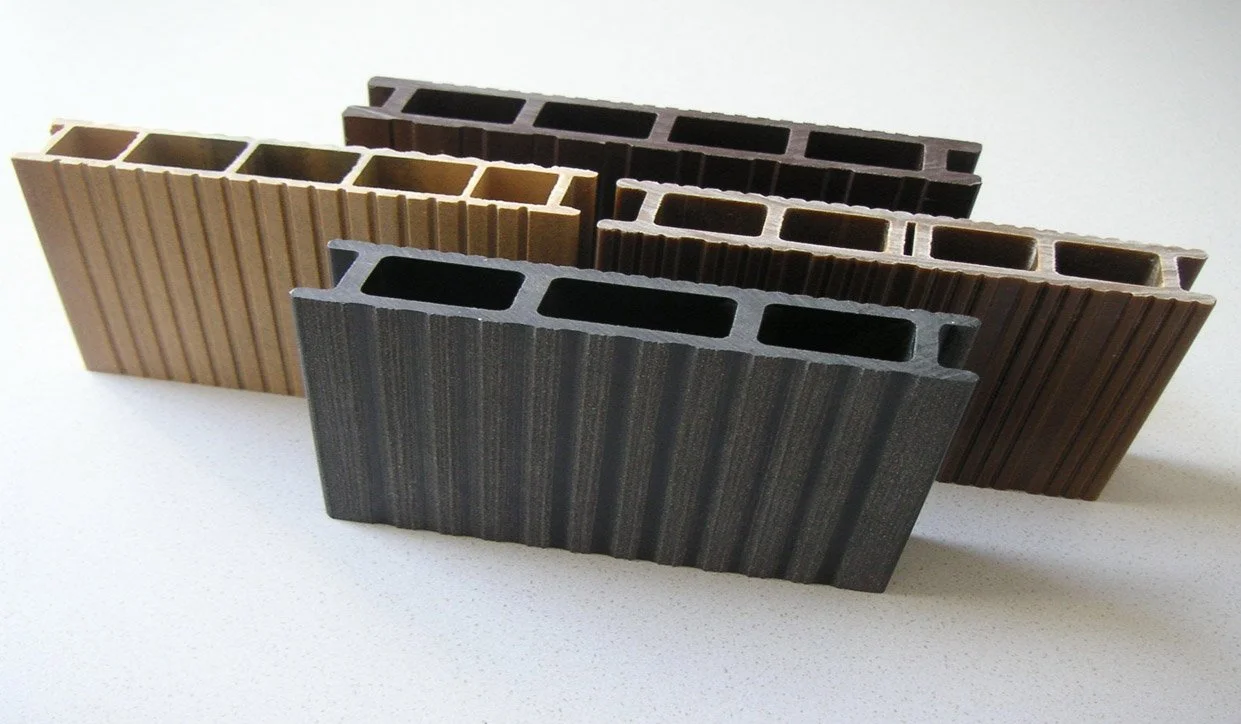 Three different types of hollow rectangular building bricks in black, brown, and gray colors, arranged in a row on a white surface.