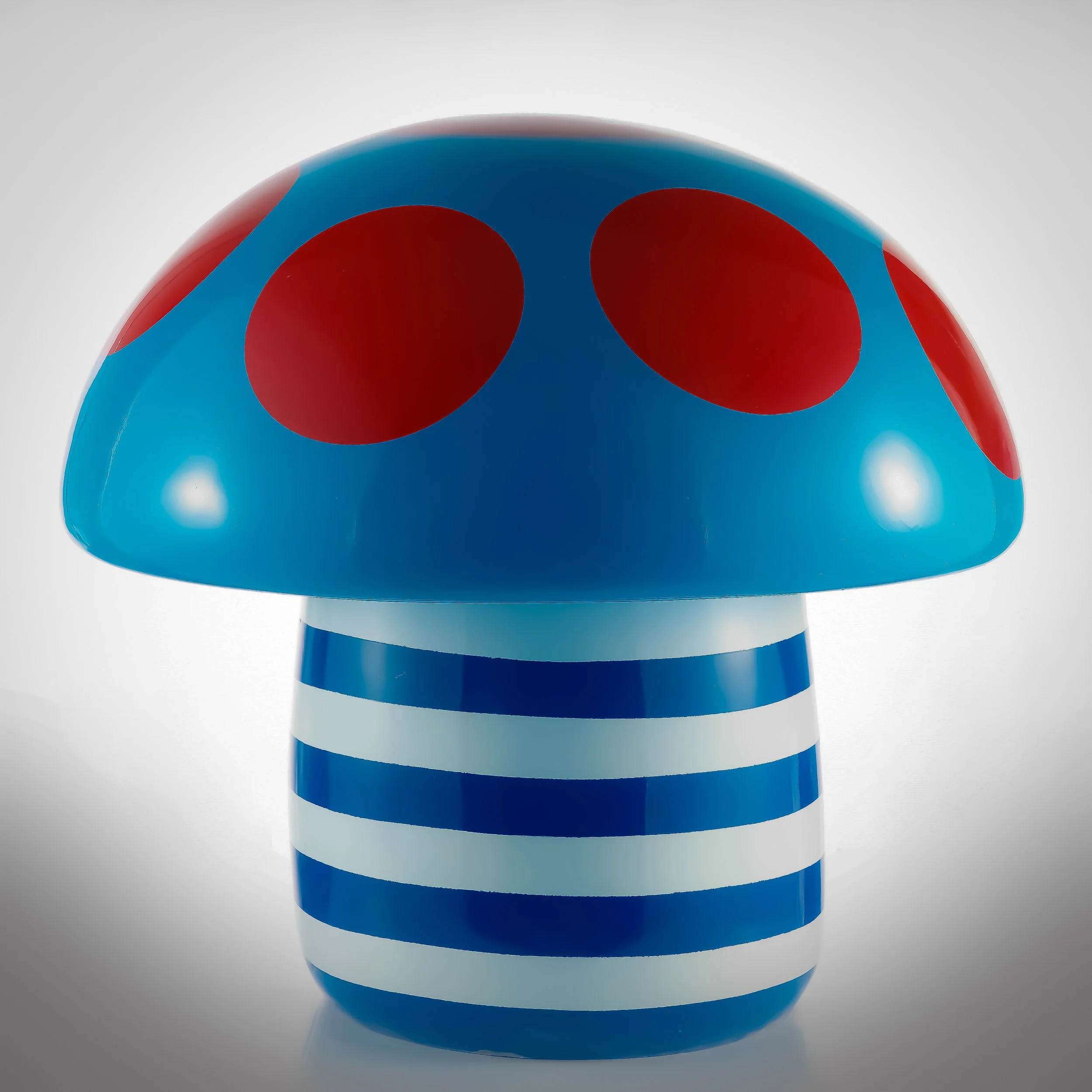 Colorful mushroom-shaped object with a blue cap featuring red spots and a striped blue and white stem.