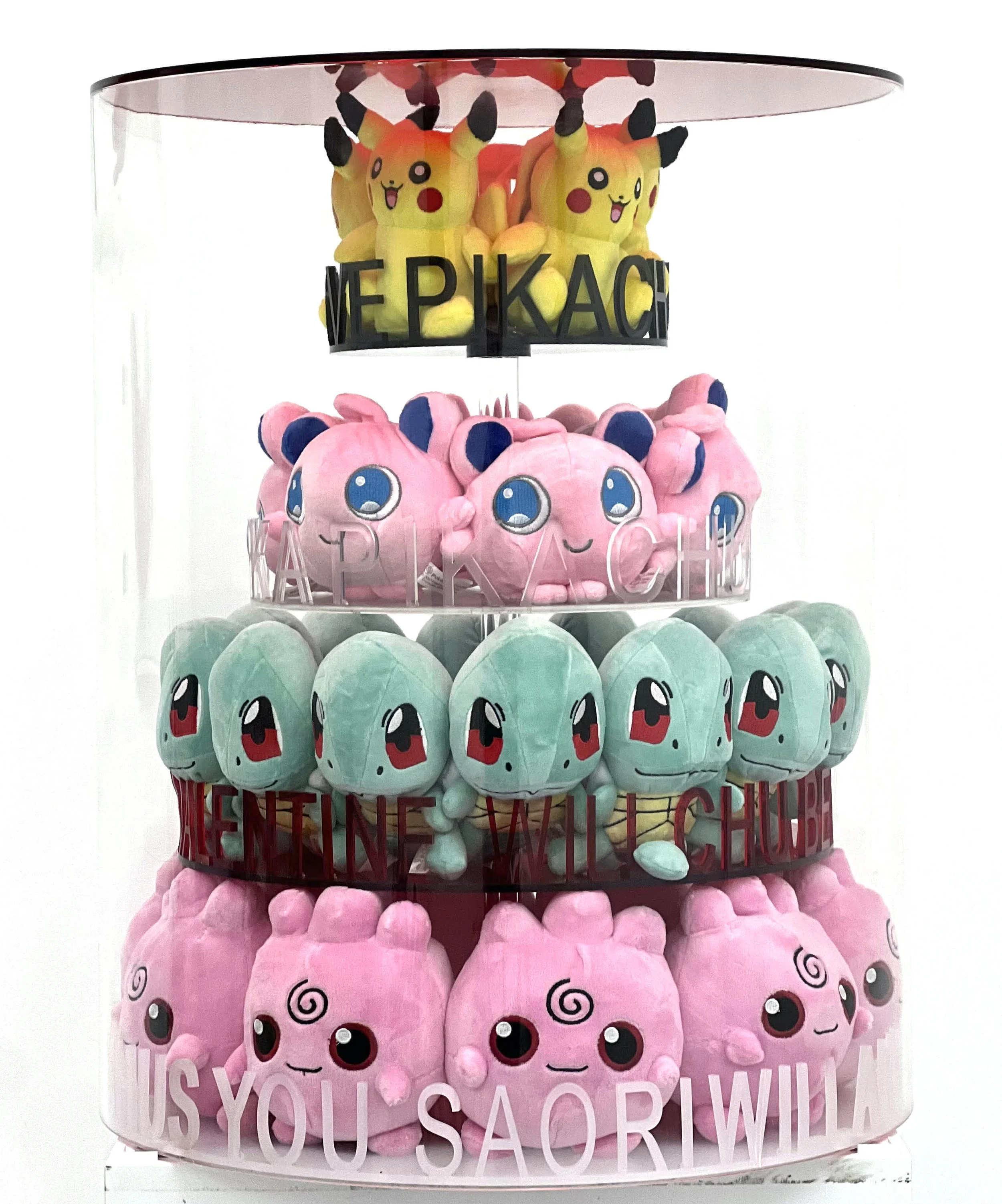 Four-tier display of Pikachu plush toys, with the top tier featuring yellow Pikachus, the second tier pink plush toys with large blue eyes, the third tier green Squirtle plush toys, and the bottom tier pink Whimsicott plush toys, with motivational me