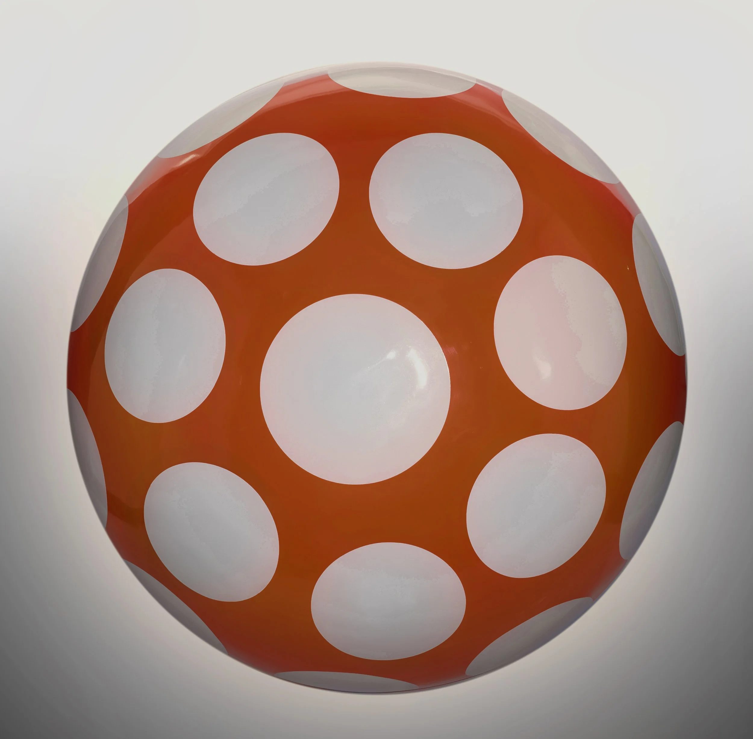 A spherical object with an orange base and large white polka dots.