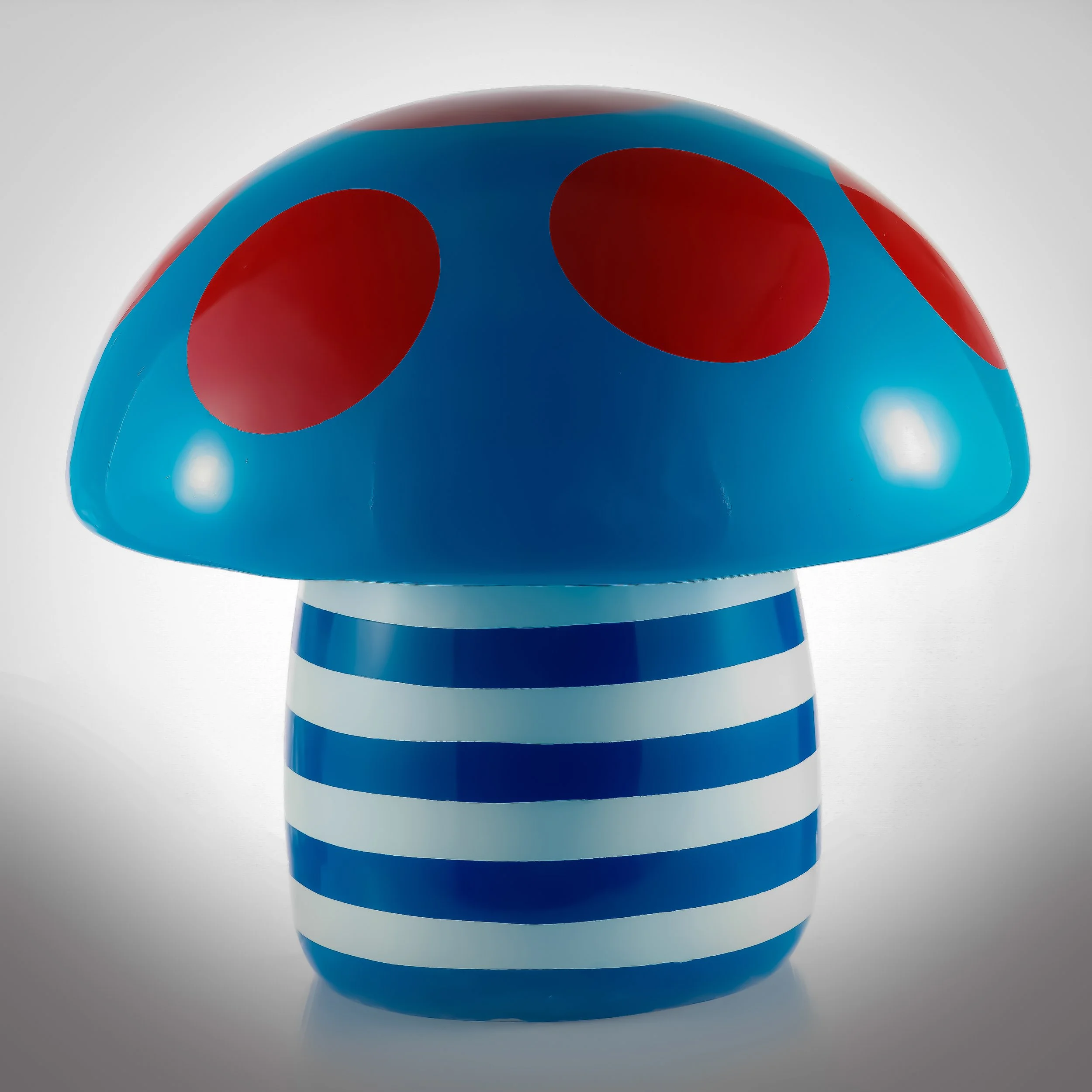 A decorative mushroom figurine with a blue cap with red spots and a blue-and-white striped stem.