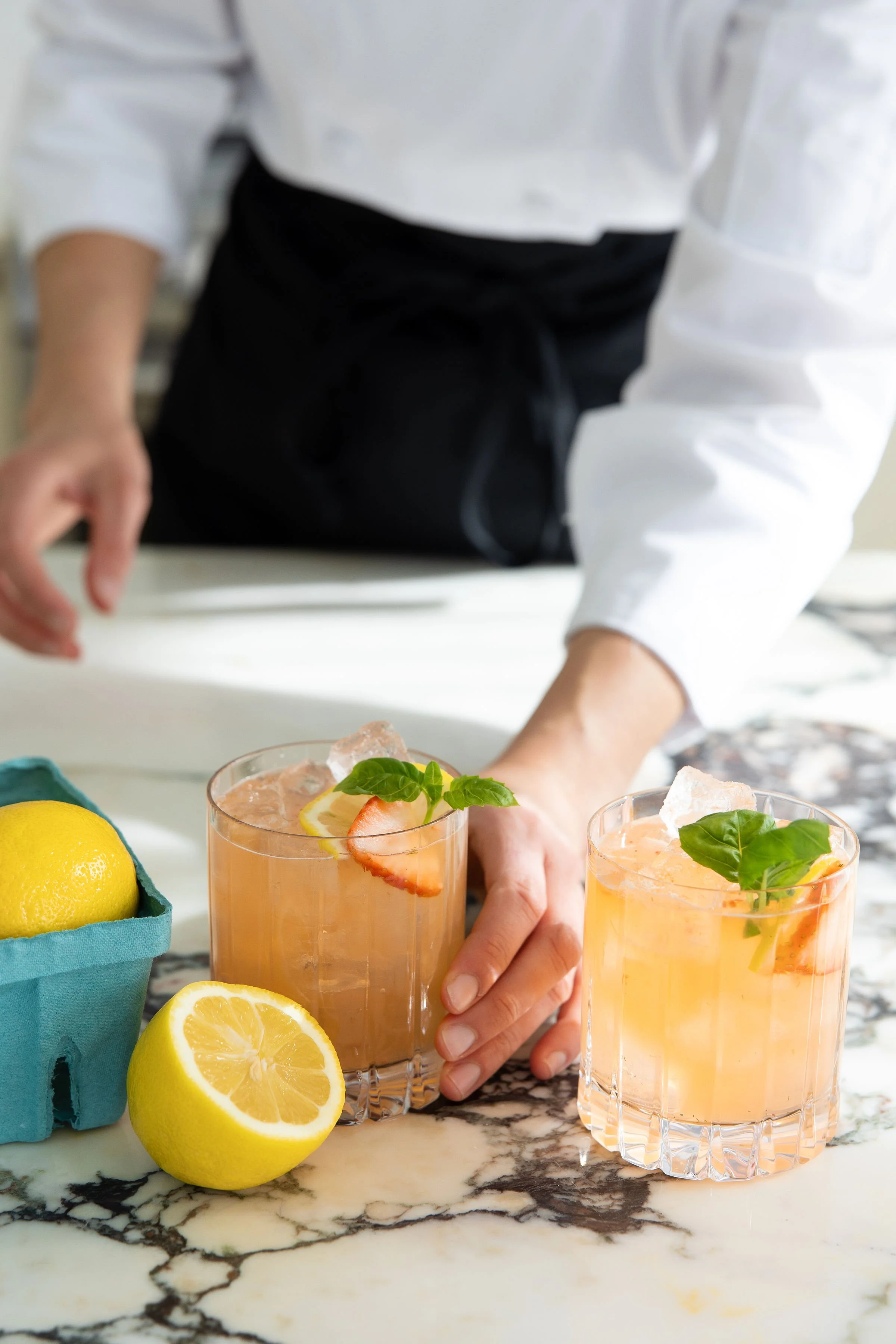 Chef Danielle of In Good Company placing a strawberry basil lemonade mocktail on a marble counter, a signature welcome drink for private dinner events in Rhode Island and Massachusetts