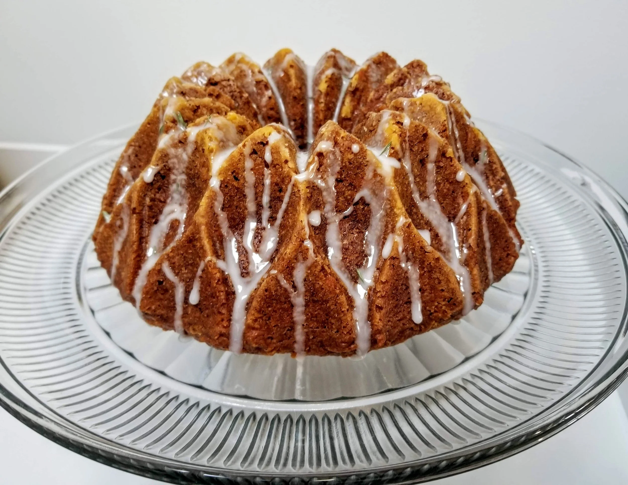 Bundt cake with drizzle on a glass cake stand.