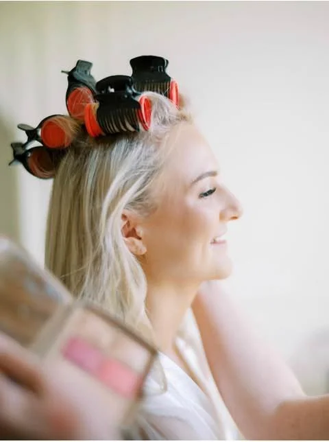 Woman with blonde hair wearing hair rollers in a salon.