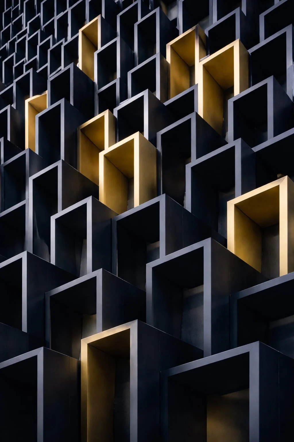 Close-up of a modern architectural wall with black and gold rectangular open boxes arranged in a geometric pattern.