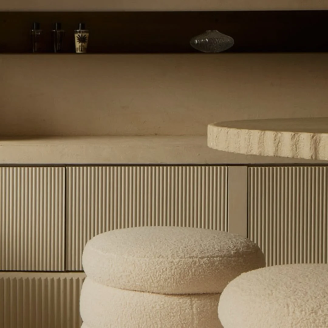 Interno con mobili in stile minimalista, presenza di una parete con ante a rientro, alcune ciotole tonde di colore chiaro e una mensola superiore con oggetti decorativi.