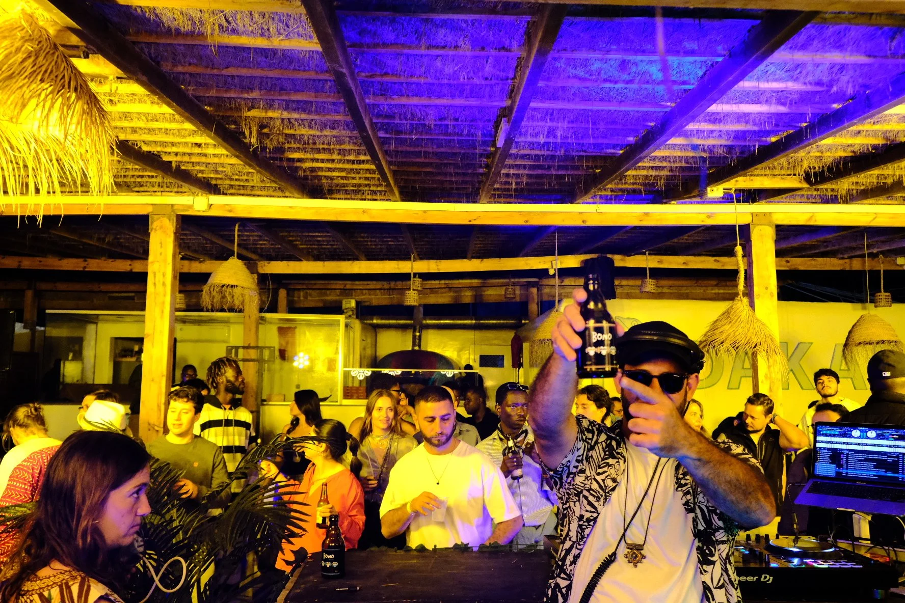 DJ holding up and pointing at a beer bottle