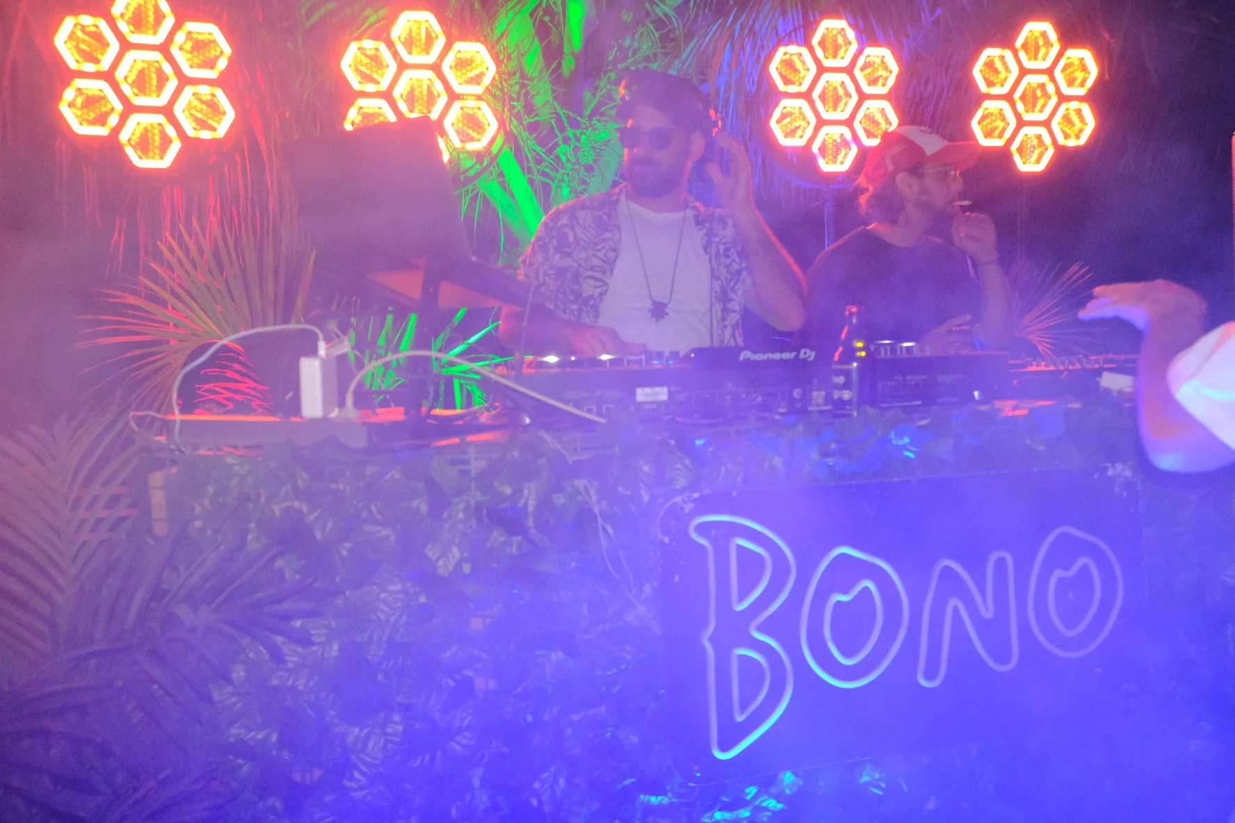 A DJ playing at a party in front of yellow spotlights 