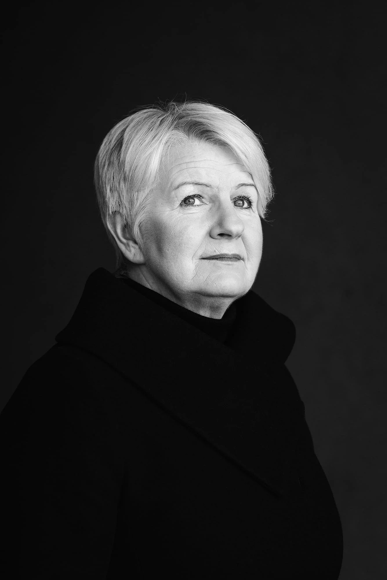 Mustavalkoinen potrettikuva naisesta tummalla taustalla