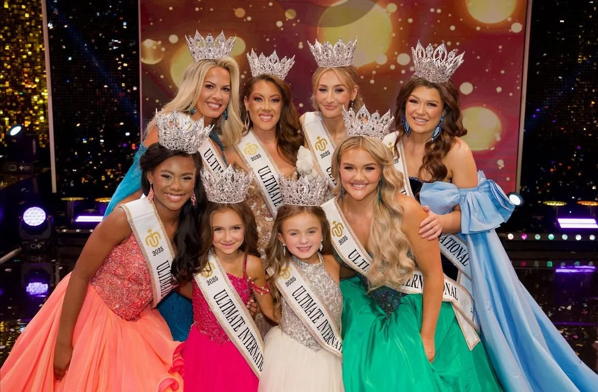 Beauty pageant contestants wearing crowns and sashes, posing on stage after winning