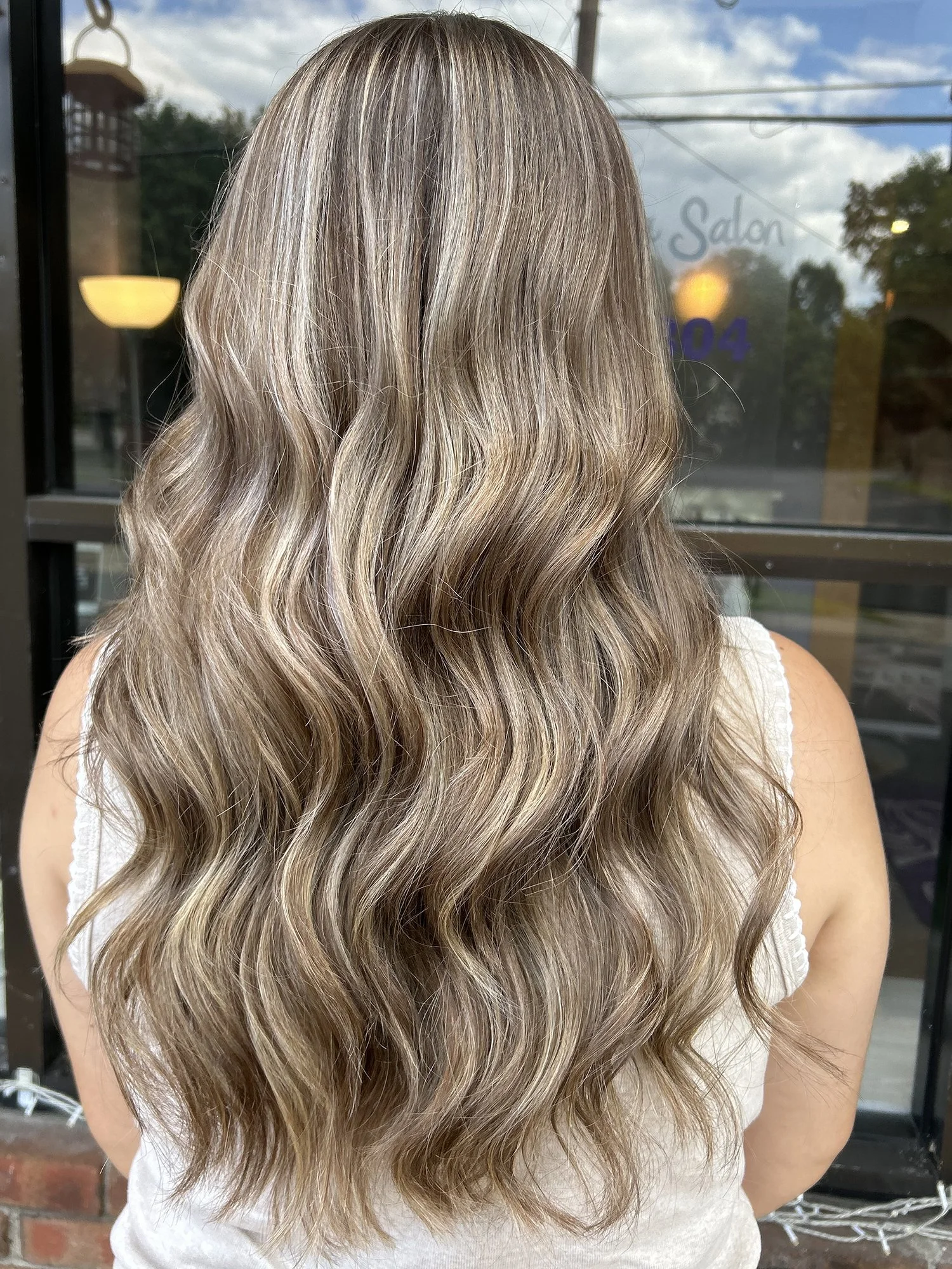 Long ash brown hairstyle with highlights and waves.