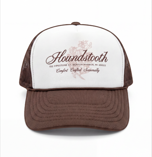 A trucker cap with a white front panel, brown brim, and brown mesh back. The front panel features the word 'Houndstooth' with floral designs and additional text.
