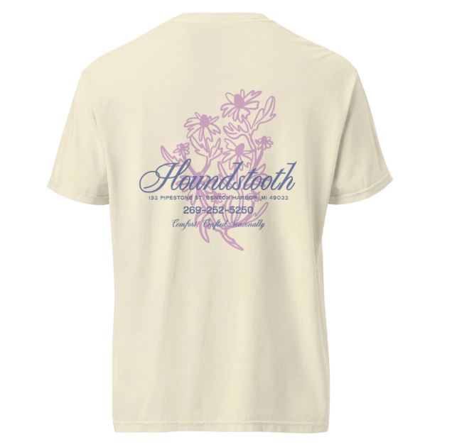 Cream-colored T-shirt with a purple floral design and text on the back that reads "Houndstooth," with an address and phone number below.