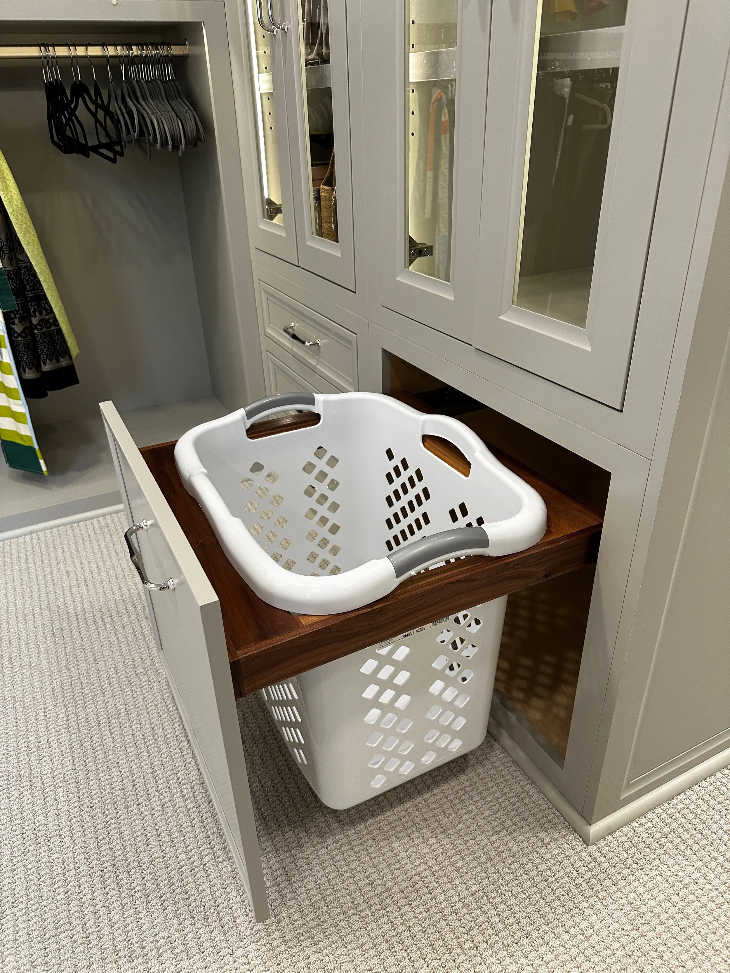Open closet with hanging clothes, a laundry hamper with a wipeable plastic liner, and a wooden countertop.