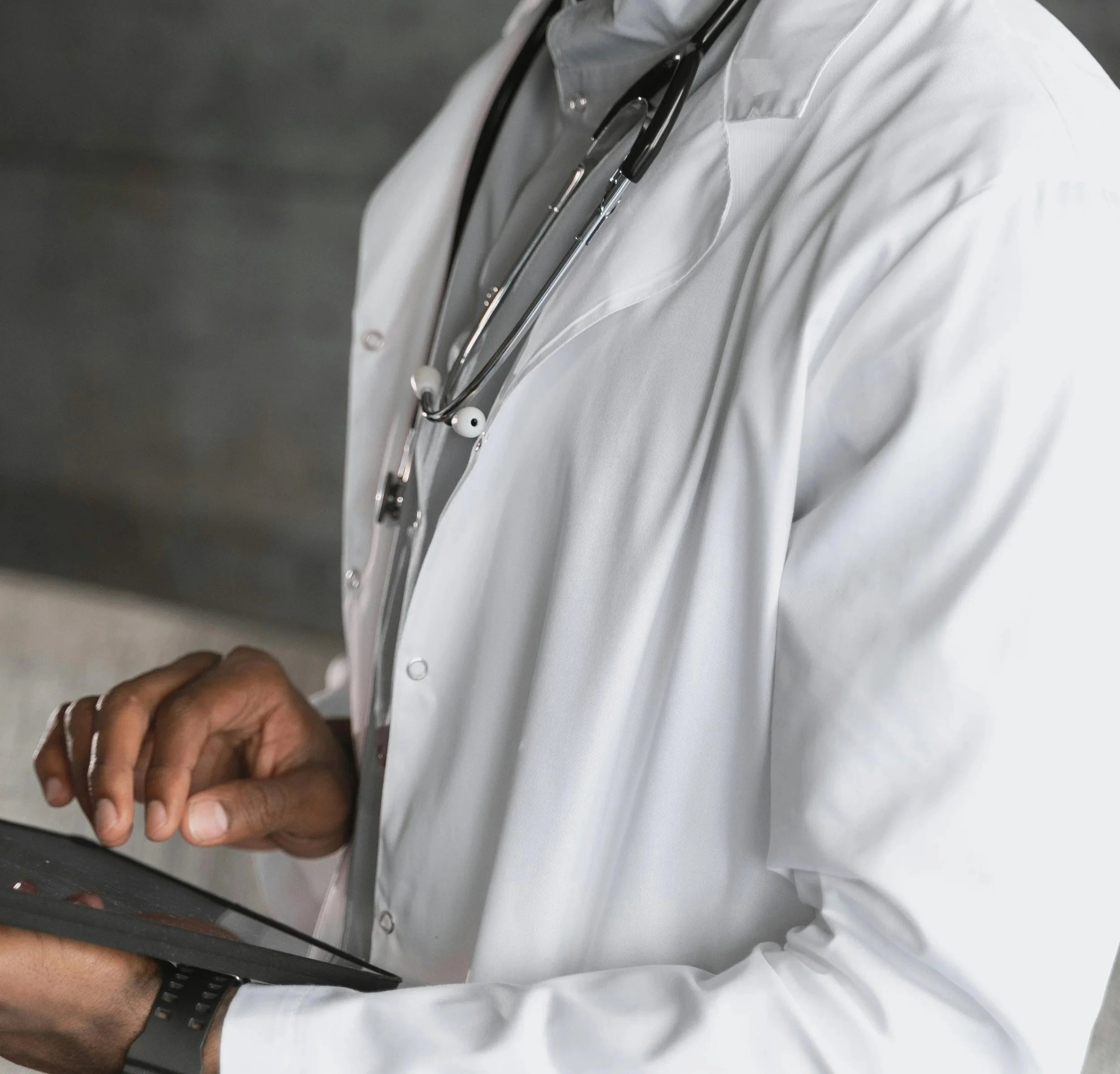 Close-up of a person's hand holding a smartphone, taking a photo of a doctor wearing a white coat and a stethoscope around their neck.