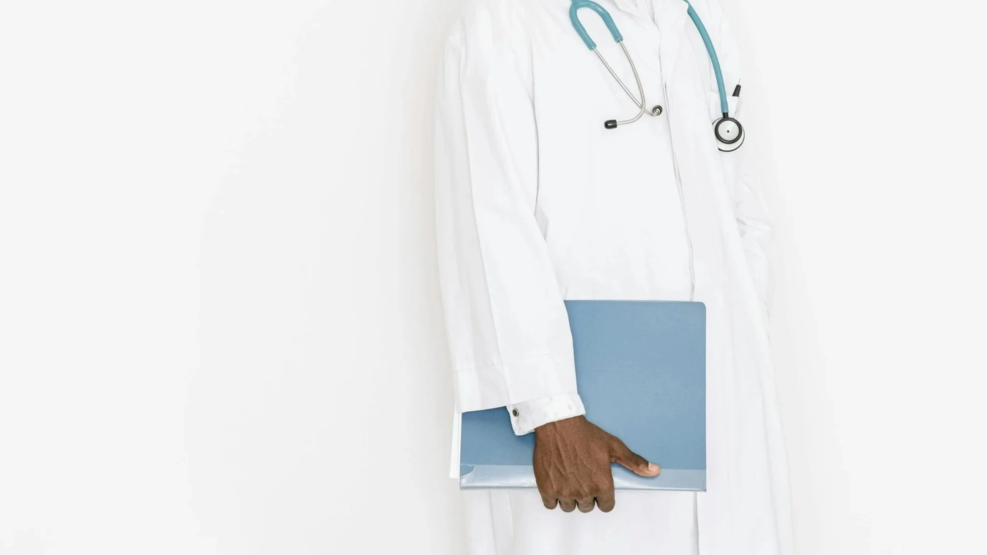 Close-up of a doctor or medical professional wearing a white coat with a stethoscope and holding a blue clipboard.