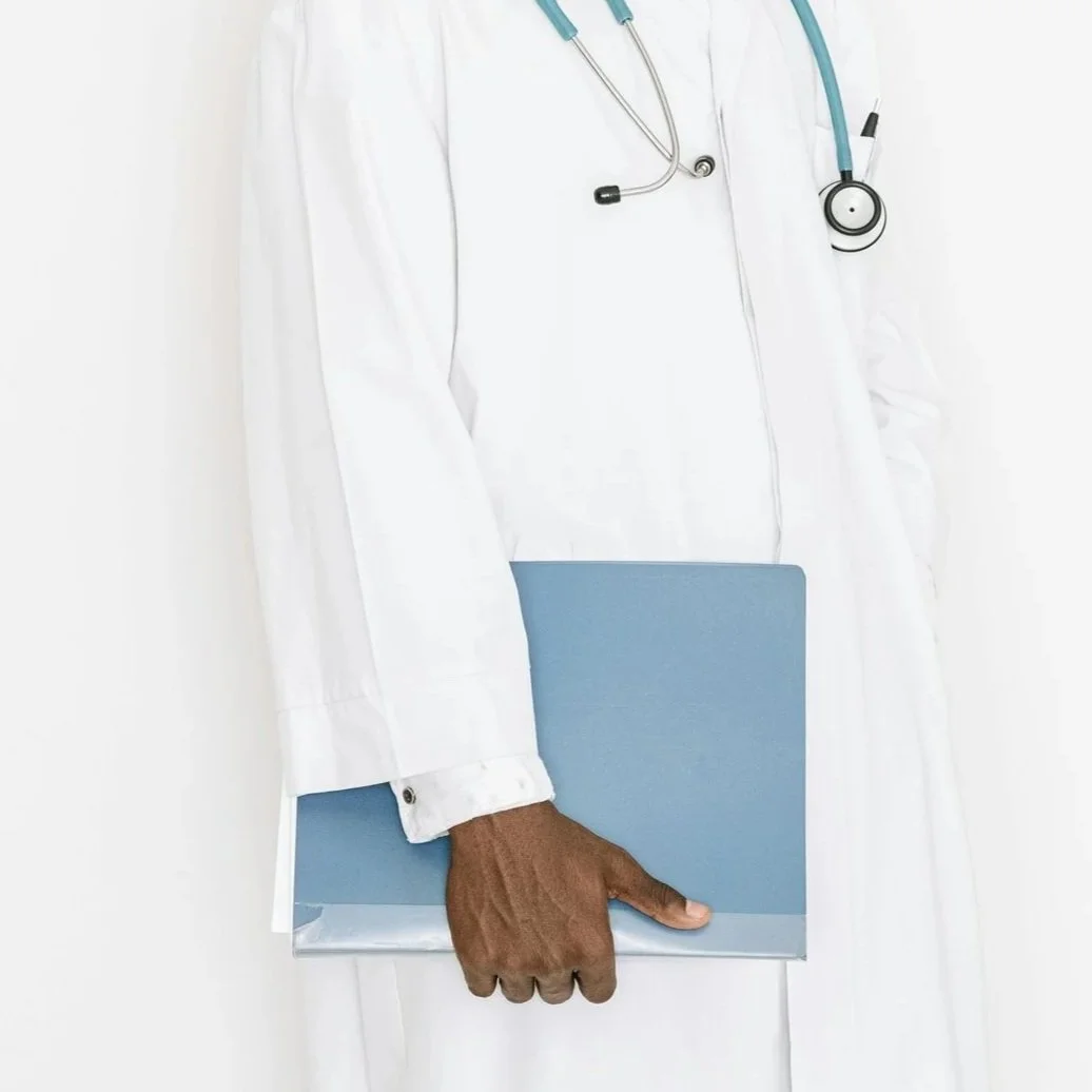 Close-up of a healthcare professional's torso wearing a white lab coat with a stethoscope around their neck, holding a blue clipboard in their left hand.