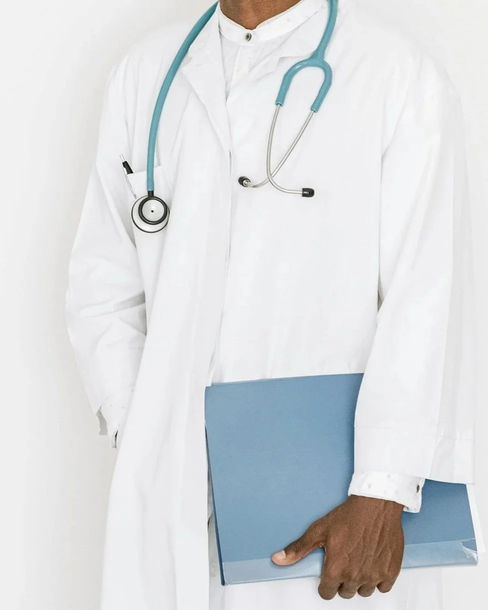 Close-up of a doctor wearing a white lab coat with a blue stethoscope around the neck, holding a blue folder.