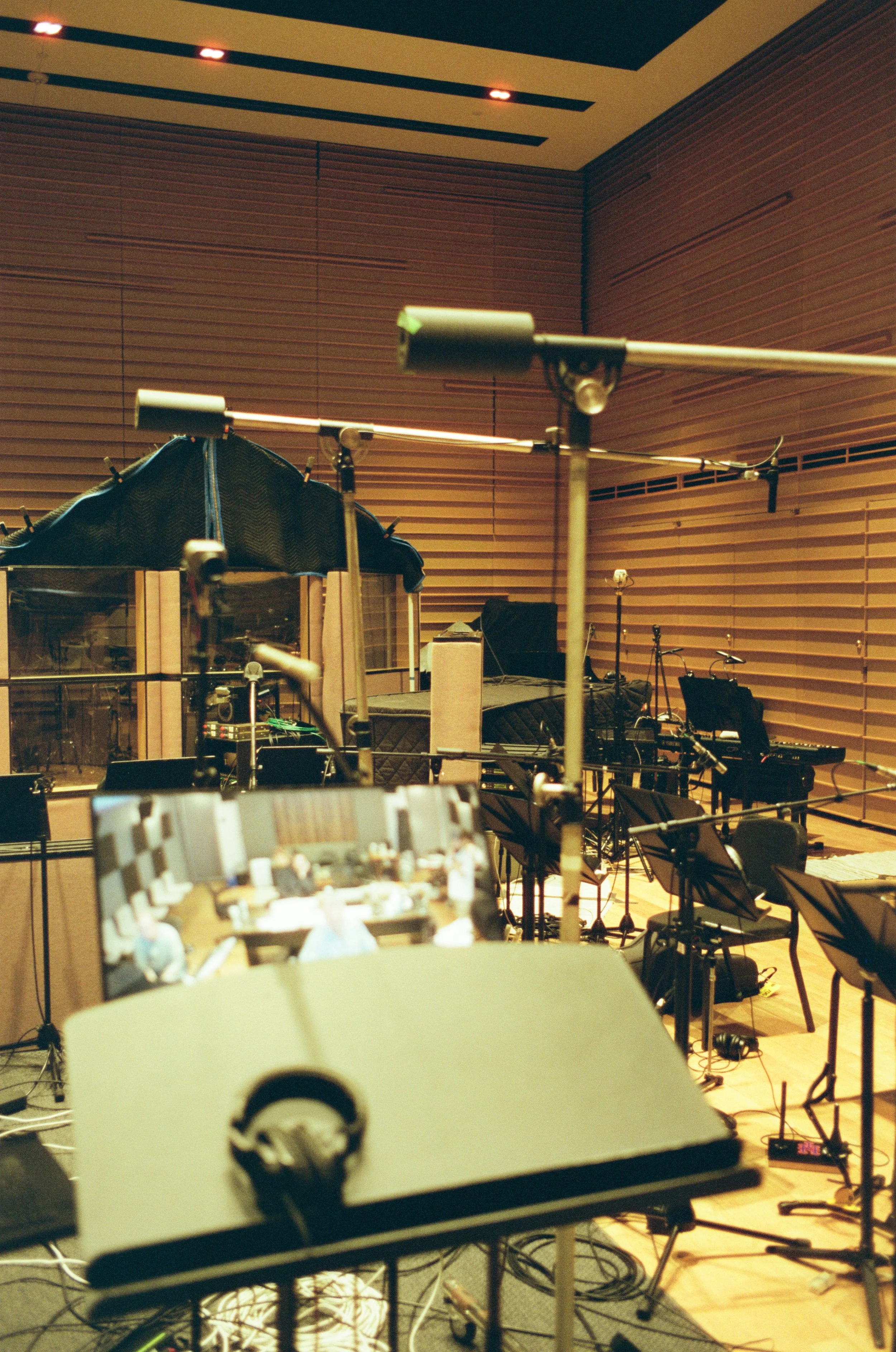 Music studio with sound equipment, music stands, and musical instruments in a room with wooden panel walls.