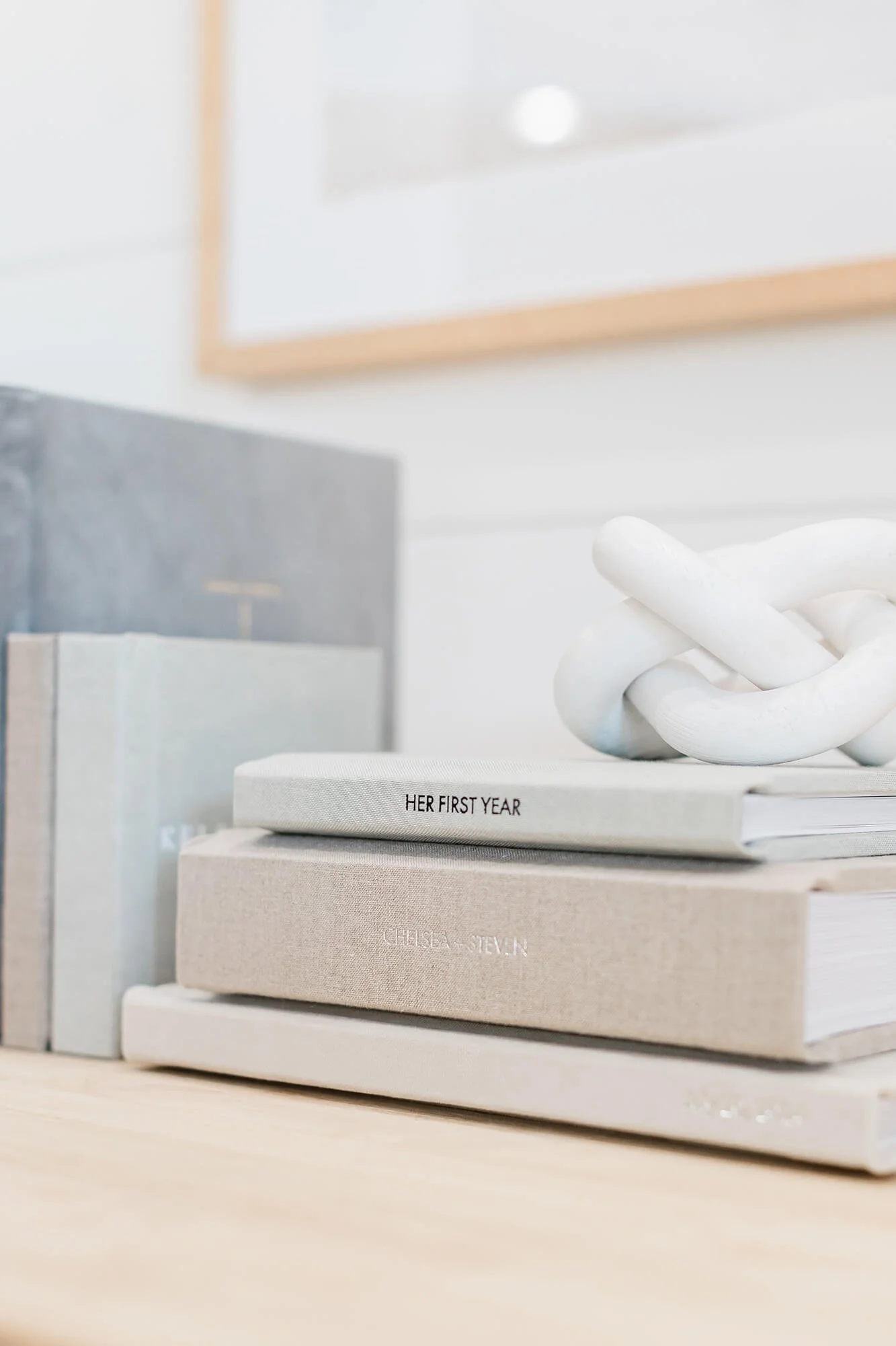 Stack of fine art heirloom family photo albums displayed in a bright home.