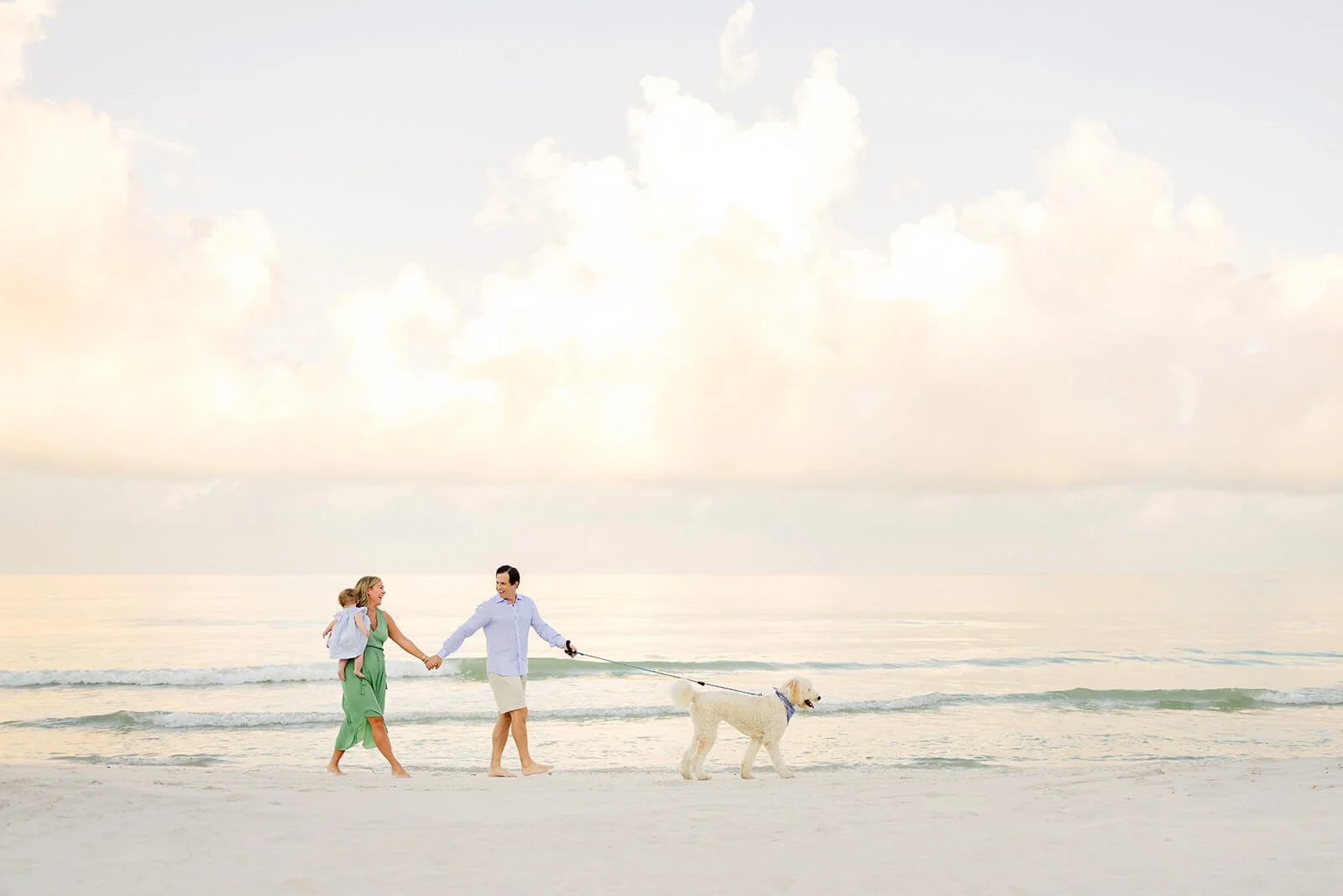 Family walking on the beach with a dog during sunrise during a portrait session in Naples, Fl.