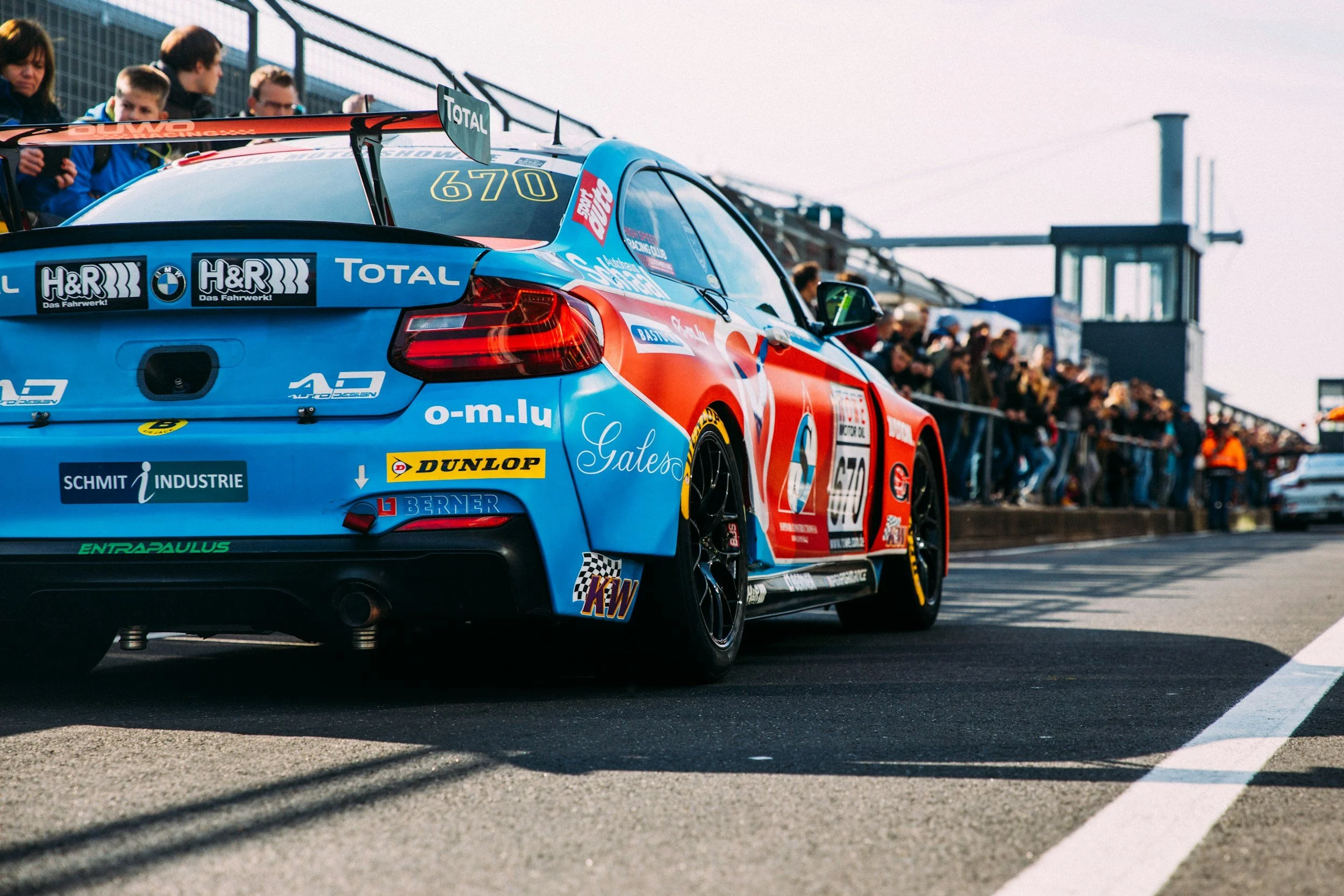 Race cars on a racetrack with spectators watching from the stands.