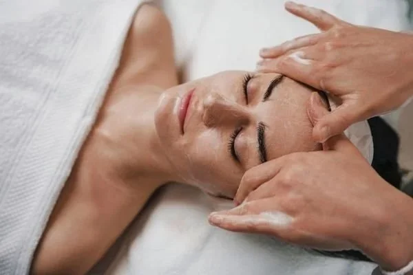 A woman receiving a facial massage in a spa or salon setting.