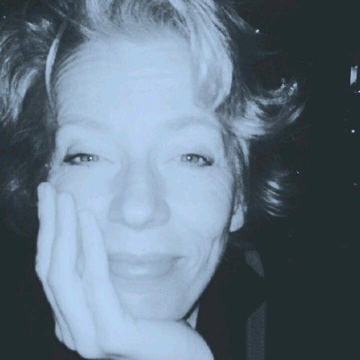 Nahaufnahme einer lachenden Frau, die die Hand die ihren Kopf mit der rechten Hand hält, das Foto ist in Schwarzweiß mit einem blauen Filter.