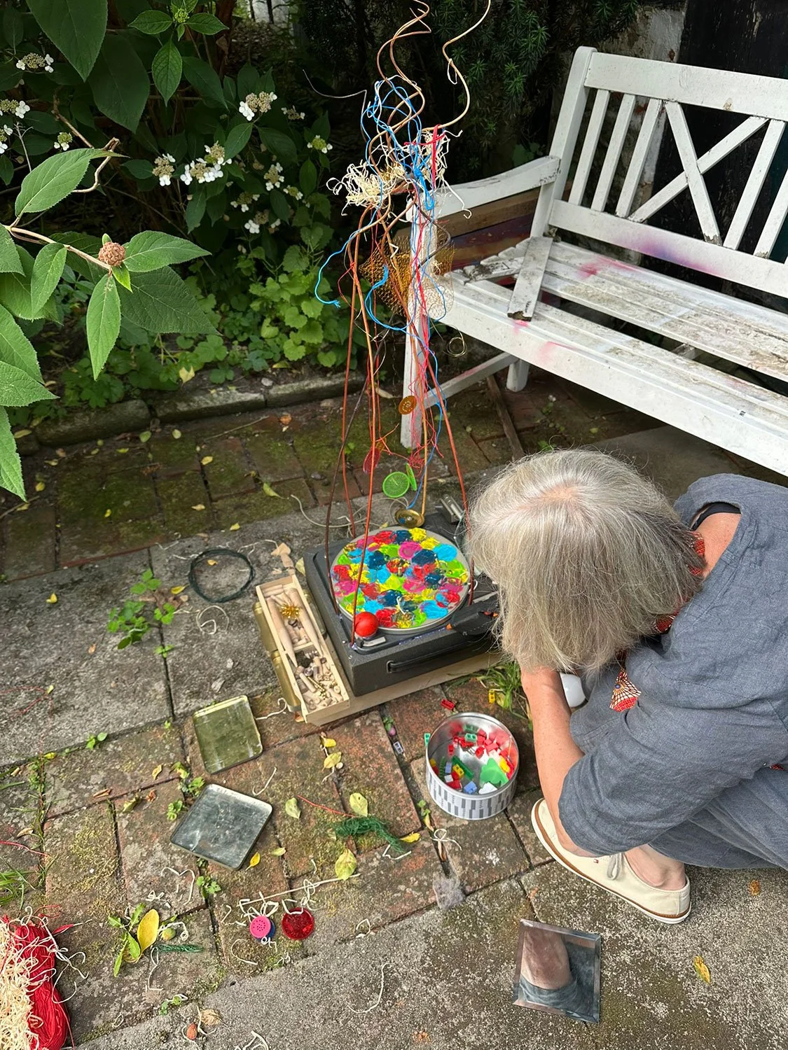 Person assembling a mixed-media sculpture from colourful found materials during an intuitive creative process