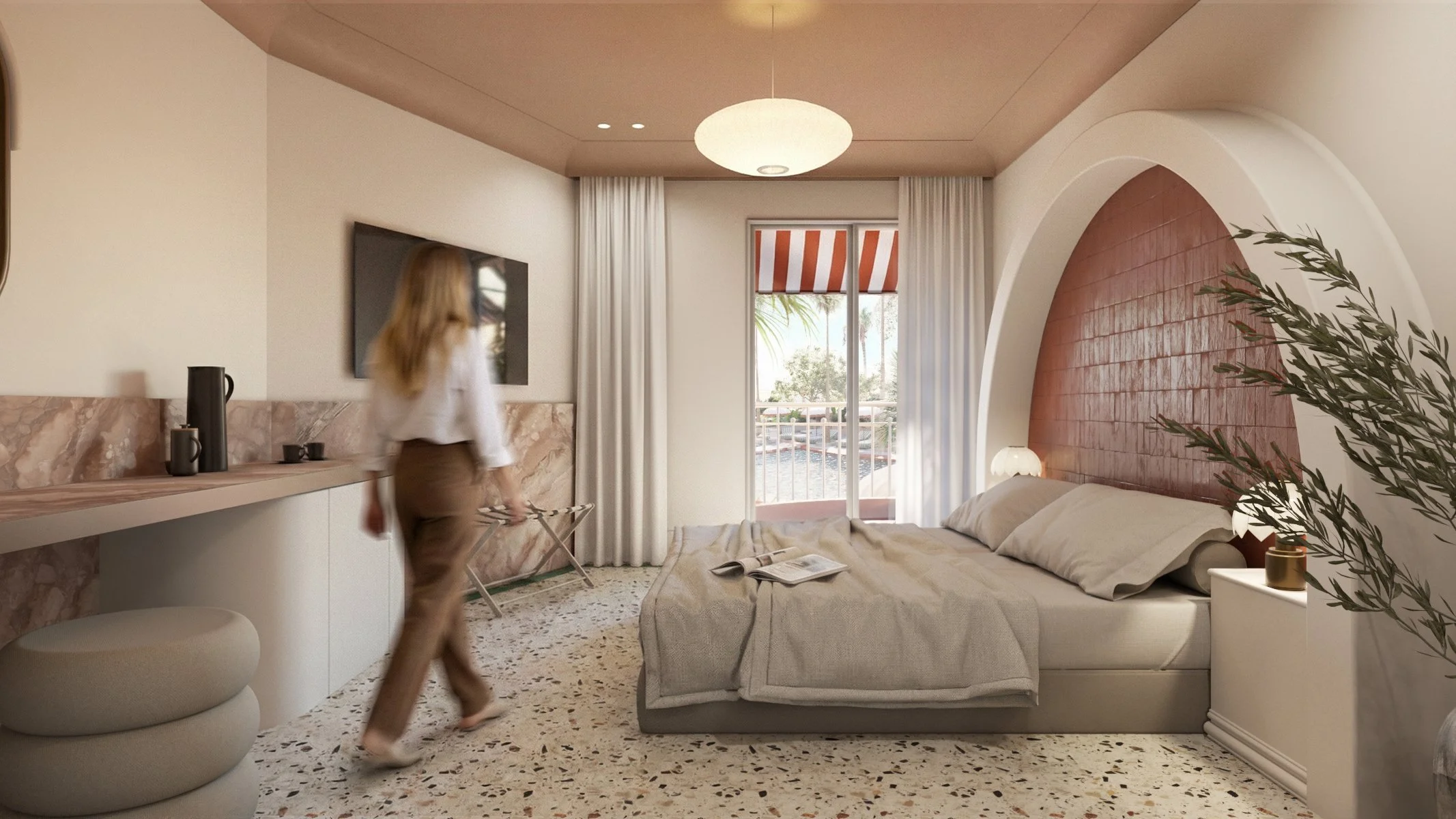 A modern bedroom with a bed against a curved red brick accent wall, a nightstand with a table lamp, and a sliding glass door with white curtains leading to a balcony. A woman with blonde hair is walking across the room, blurred.
