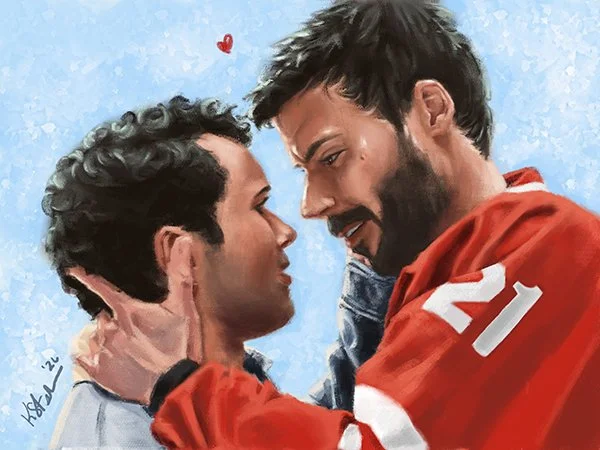 Two men face each other closely, one wearing a red sports jersey with the number 21, and the other in a light-colored shirt. The man in the jersey is holding the face of the other, both smiling, with a small red heart above their heads.