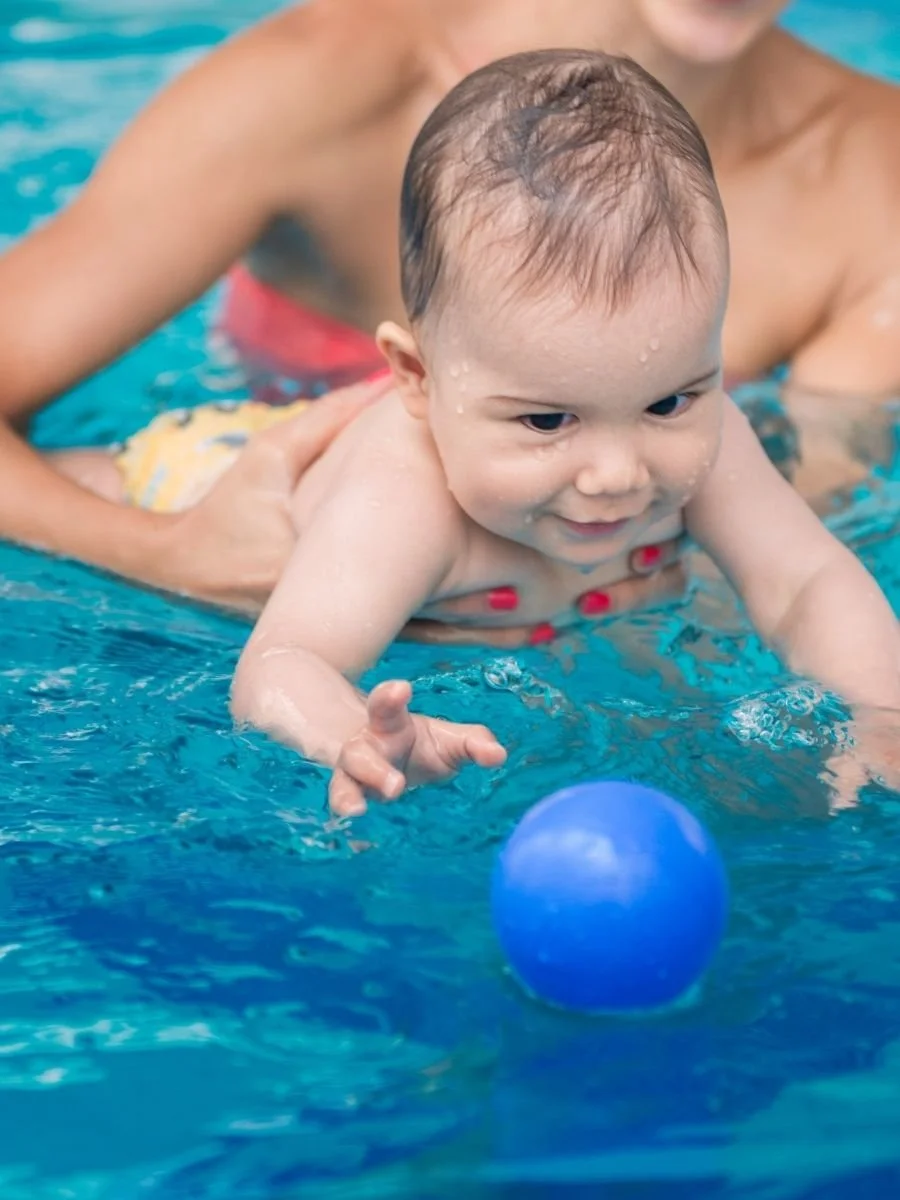 Baby learning how to swim with an instructor teaching him/her.