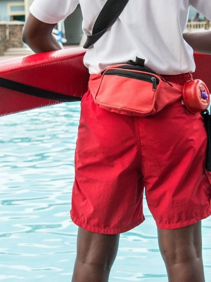Young man wearing red lifeguard swimming shorts.