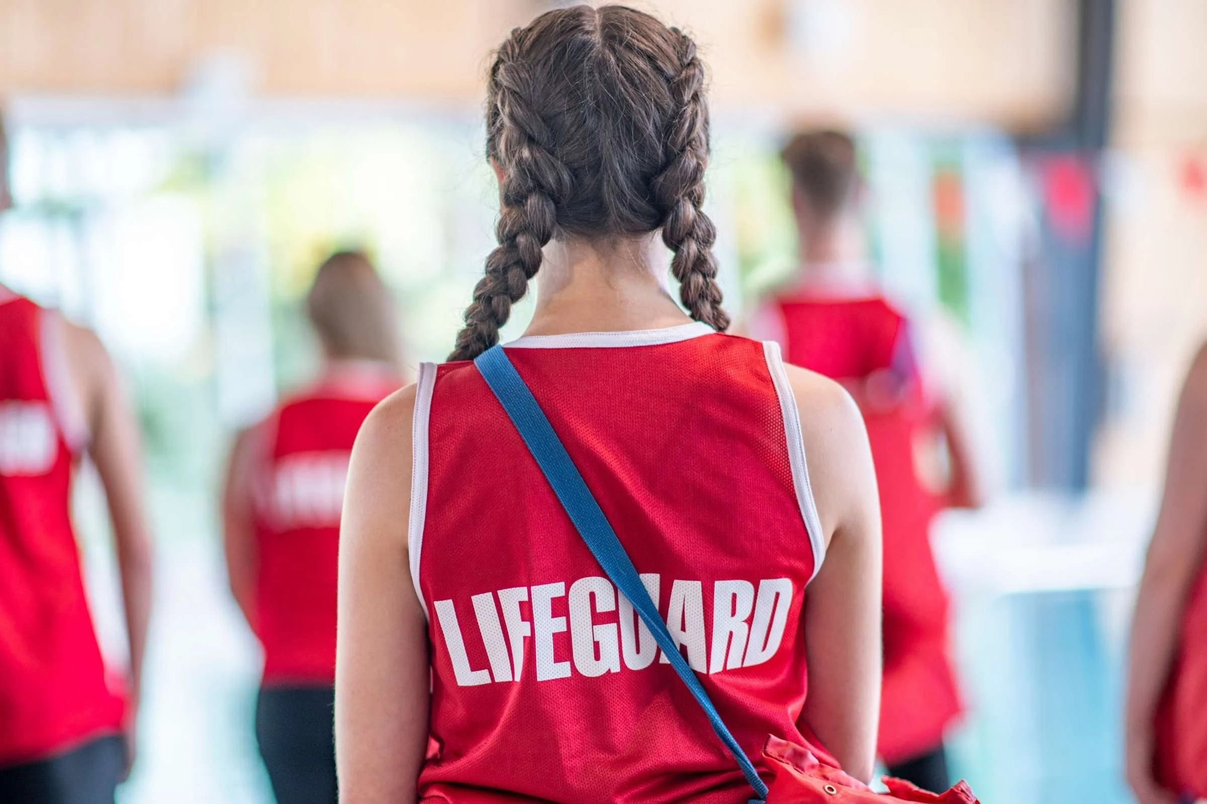 Young girl wearing a red lifeguard t-shirt.