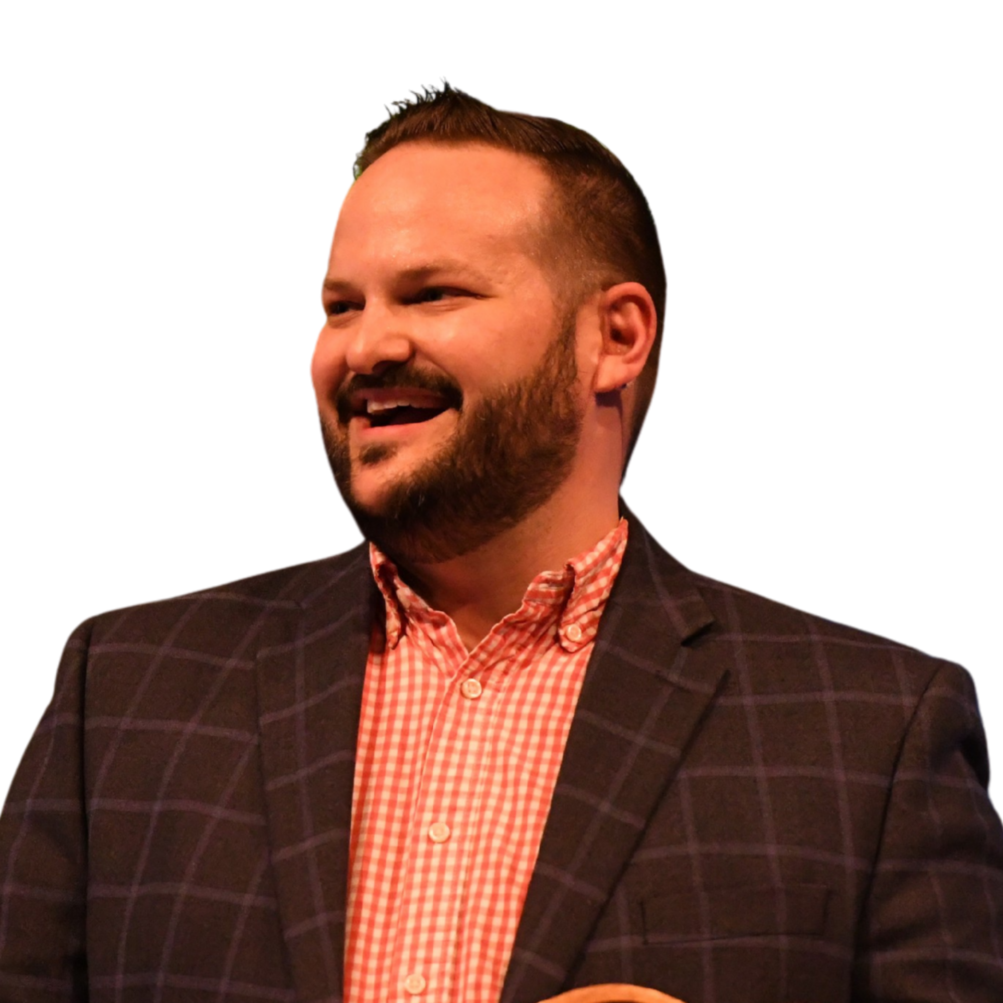 Close-up of a man with short dark hair and a beard, smiling, wearing a dark checked blazer and a red and white checked shirt.