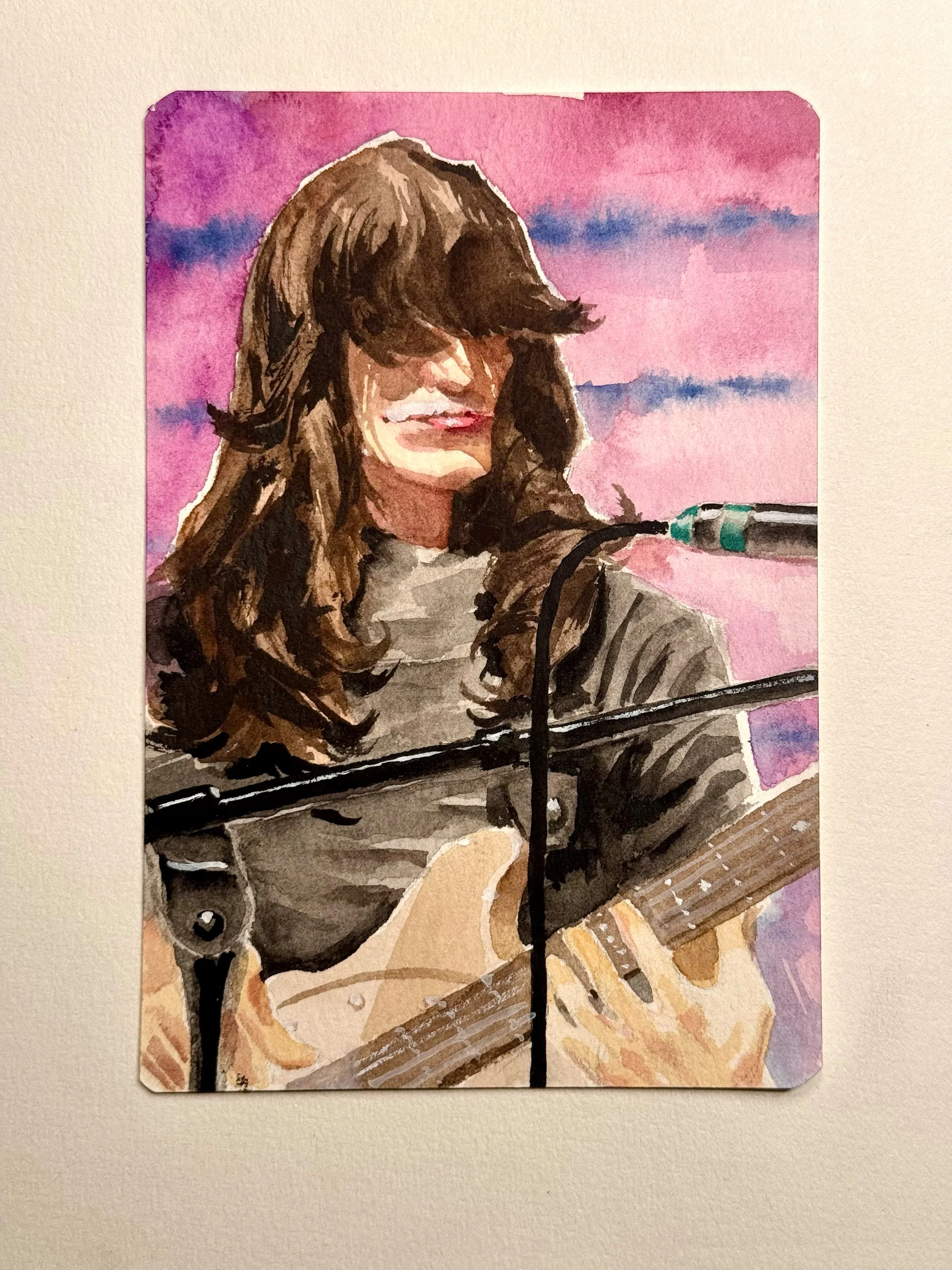 A watercolor painting of a female Man with long brown hair, playing a bass, against a pink and purple sky background.