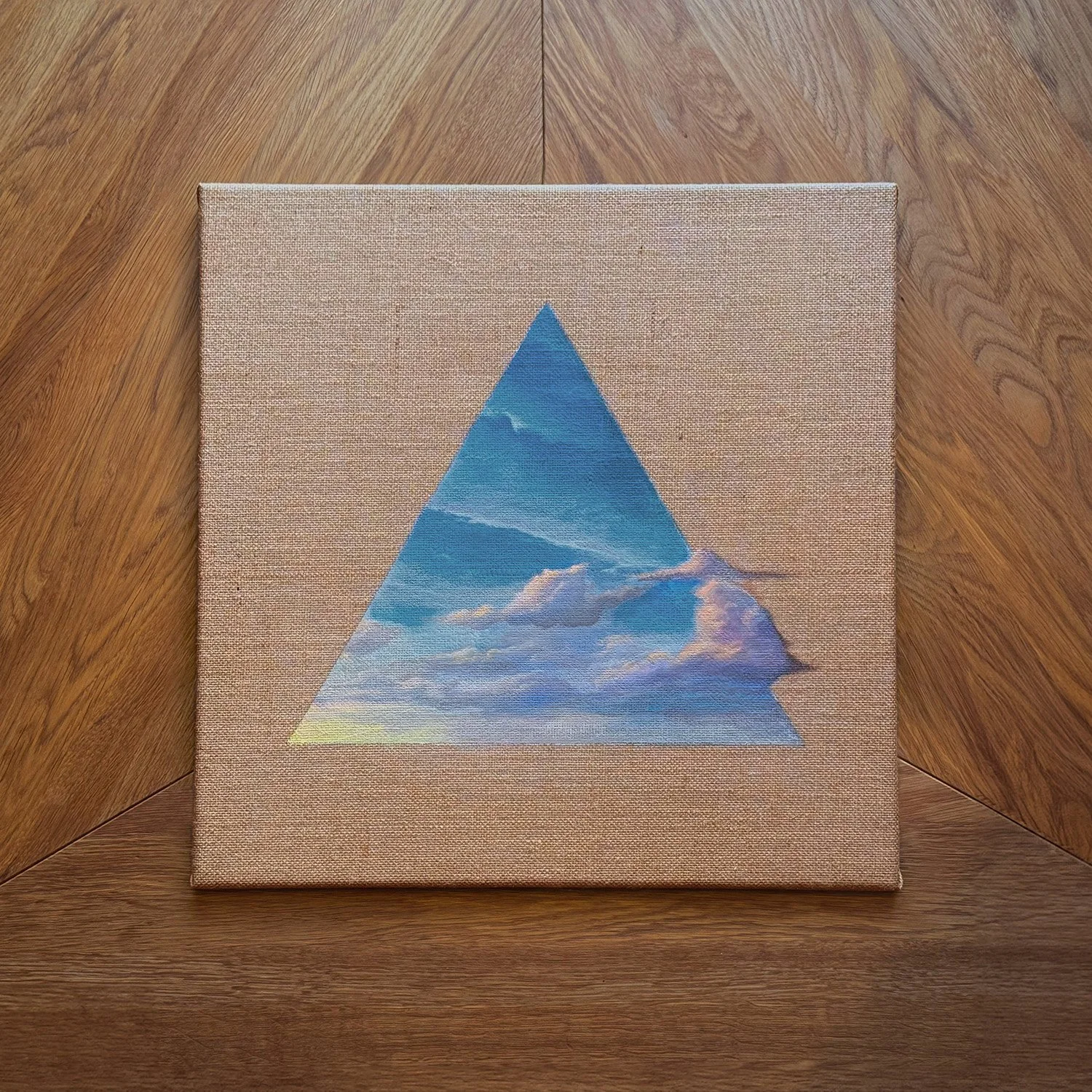 Gemaltes Bild einer Wolke im Himmel innerhalb einer blauen Pyramide, auf einem Leinwand auf Holztisch