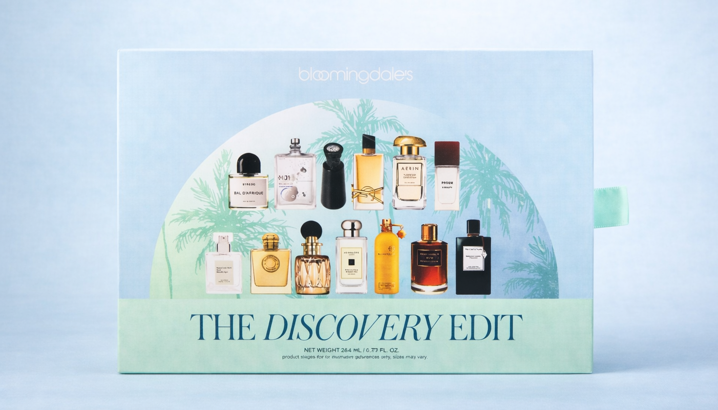 A box of assorted perfume bottles labeled 'The Discovery Edit' by Bloomingdale's with a green palm tree illustration and a light blue background.