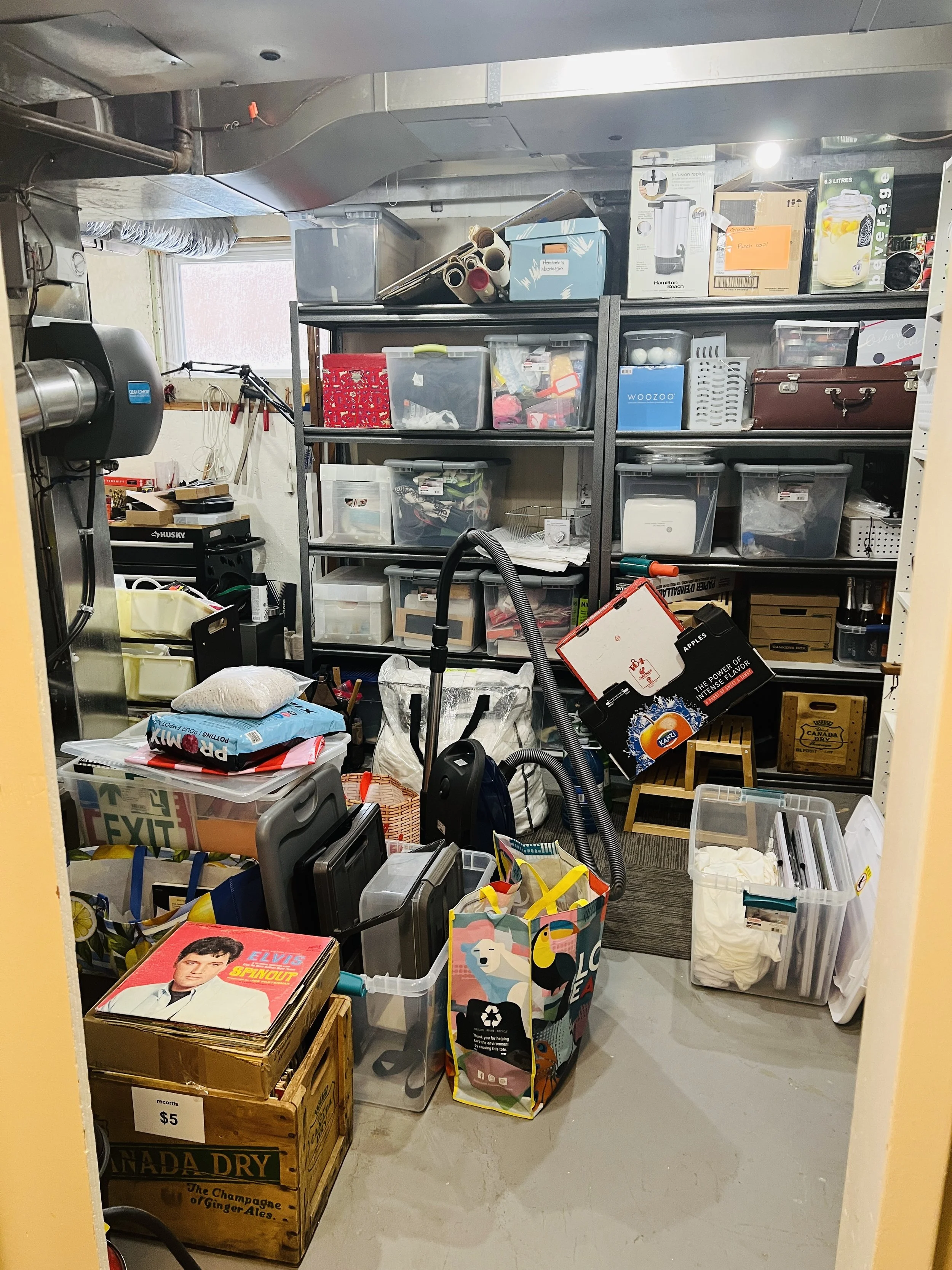 Cluttered and overwhelming furnace room full of full totes with items in the walking area