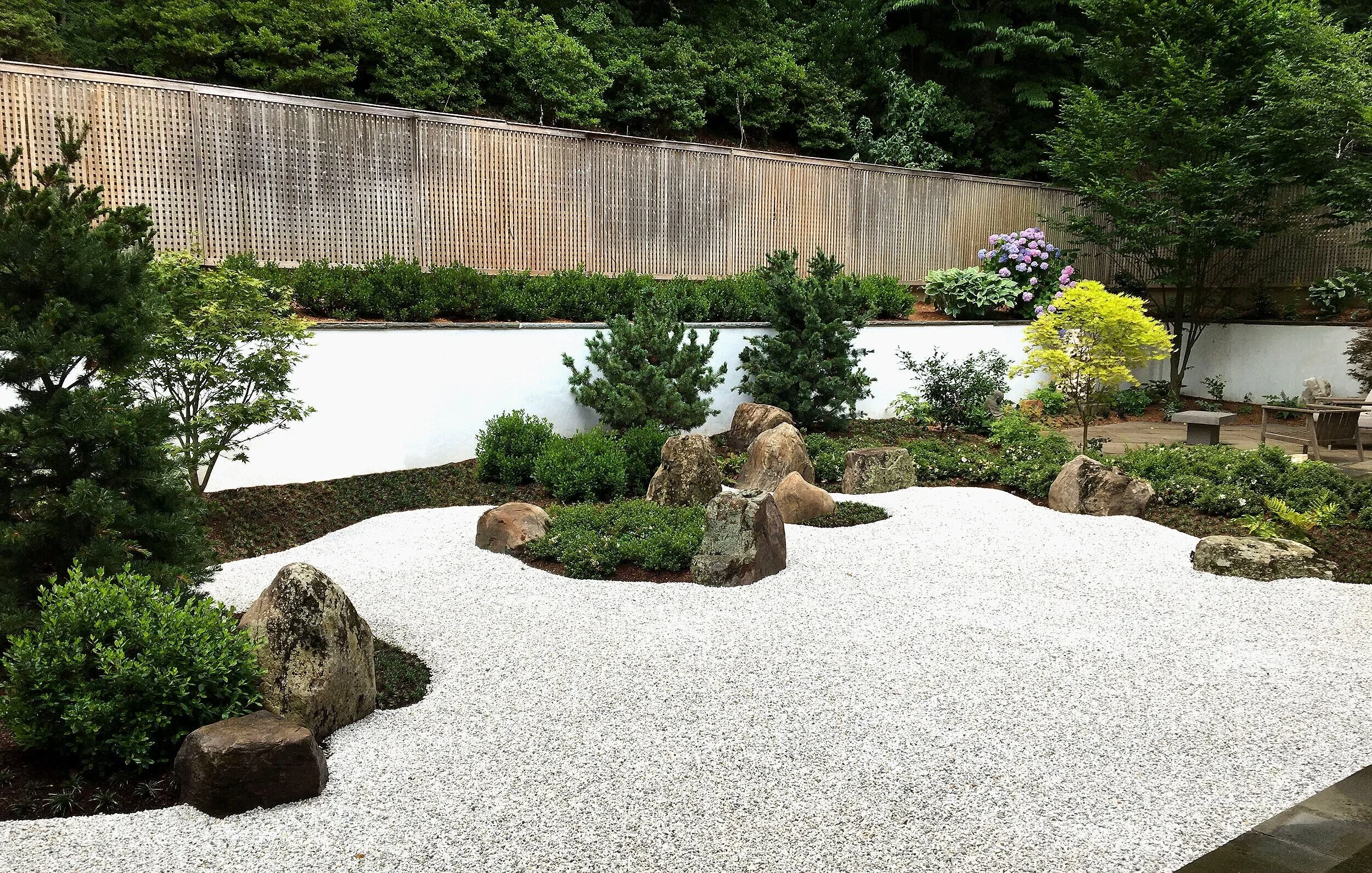 Japanese Meditation garden with gravel, boulders, pine trees and Japanese maples trees