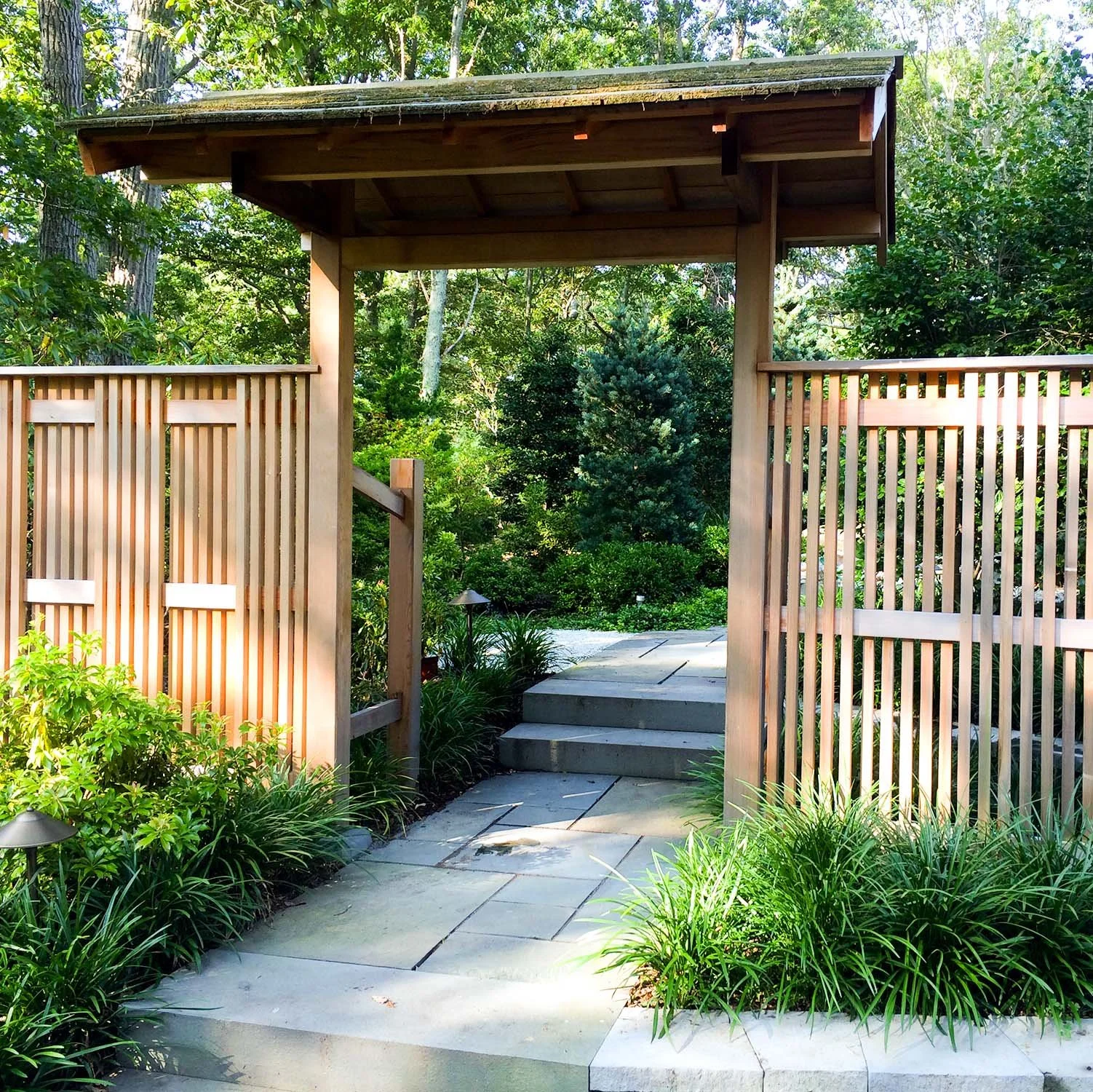 Traditional wooden gate with wooden fence leading to Japanese walkway garden